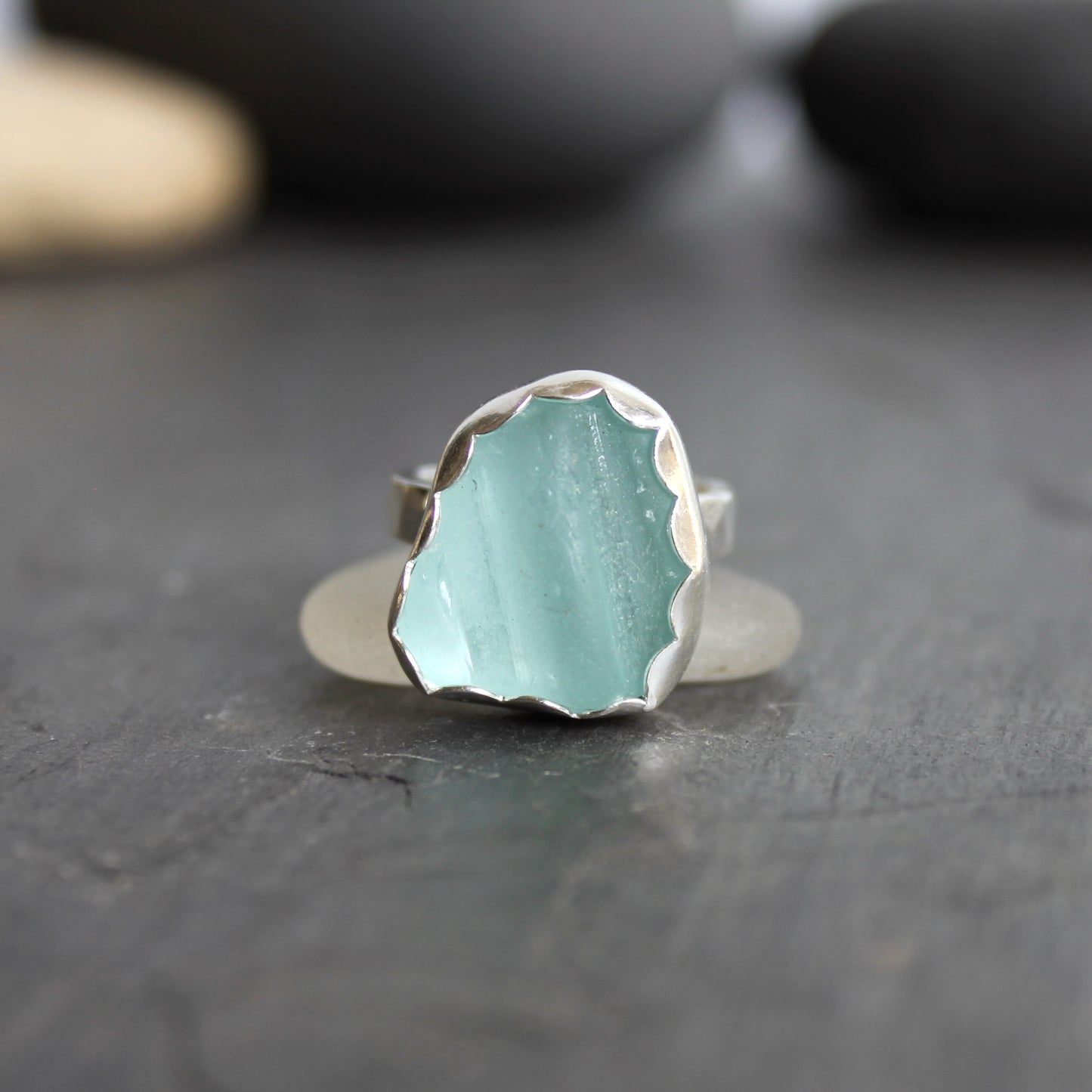 This statement ring has a pale aqua blue piece of sea glass that is set in a fine and sterling silver scalloped bezel on a sturdy hammered band. This piece is actually from a bottle neck. Handmade by Barb Macy in Corvallis, OR. Size 5 