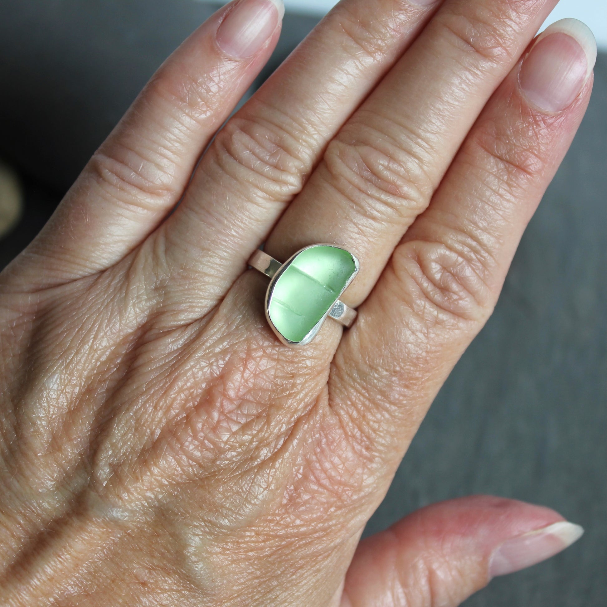 This ring has a pale yellow piece of UV uranium sea glass that is set in a fine and sterling silver bezel setting on a sturdy hammered band. Size 7 3/4 Handmade by Barb Macy in Corvallis, Oregon.