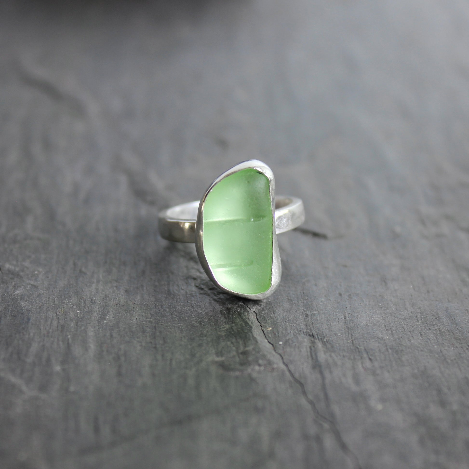 This ring has a pale yellow piece of UV uranium sea glass that is set in a fine and sterling silver bezel setting on a sturdy hammered band. Size 7 3/4 Handmade by Barb Macy in Corvallis, Oregon.