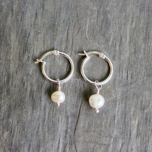 Silver hoop earrings with pearl drops on a gray wooden surface. These locking hoops are approximately 15mm in diameter with a removeable freshwater pearl drop.