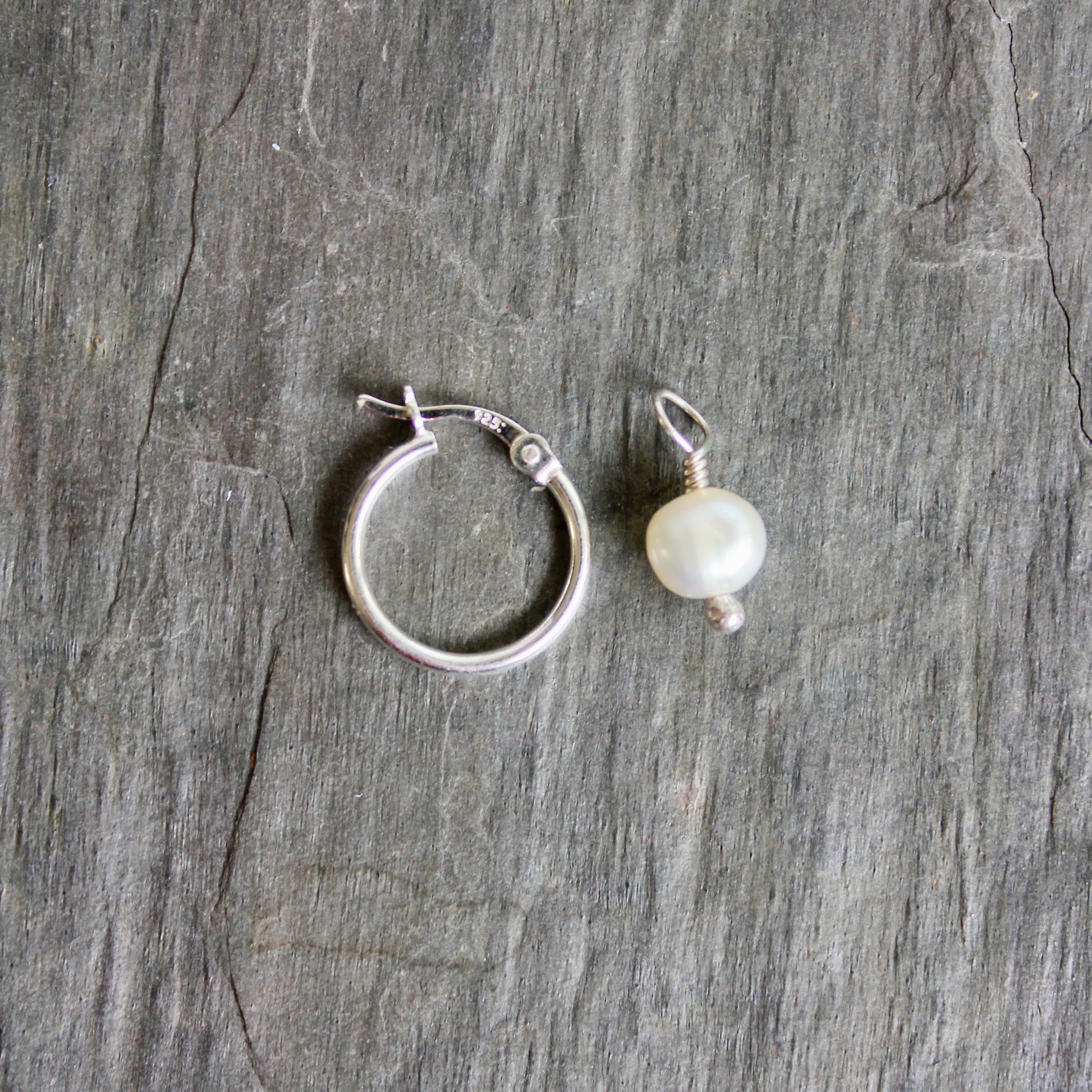 Silver hoop earring and pearl pendant on a textured gray surface. These locking hoops are approximately 15mm in diameter with a removeable freshwater pearl drop.