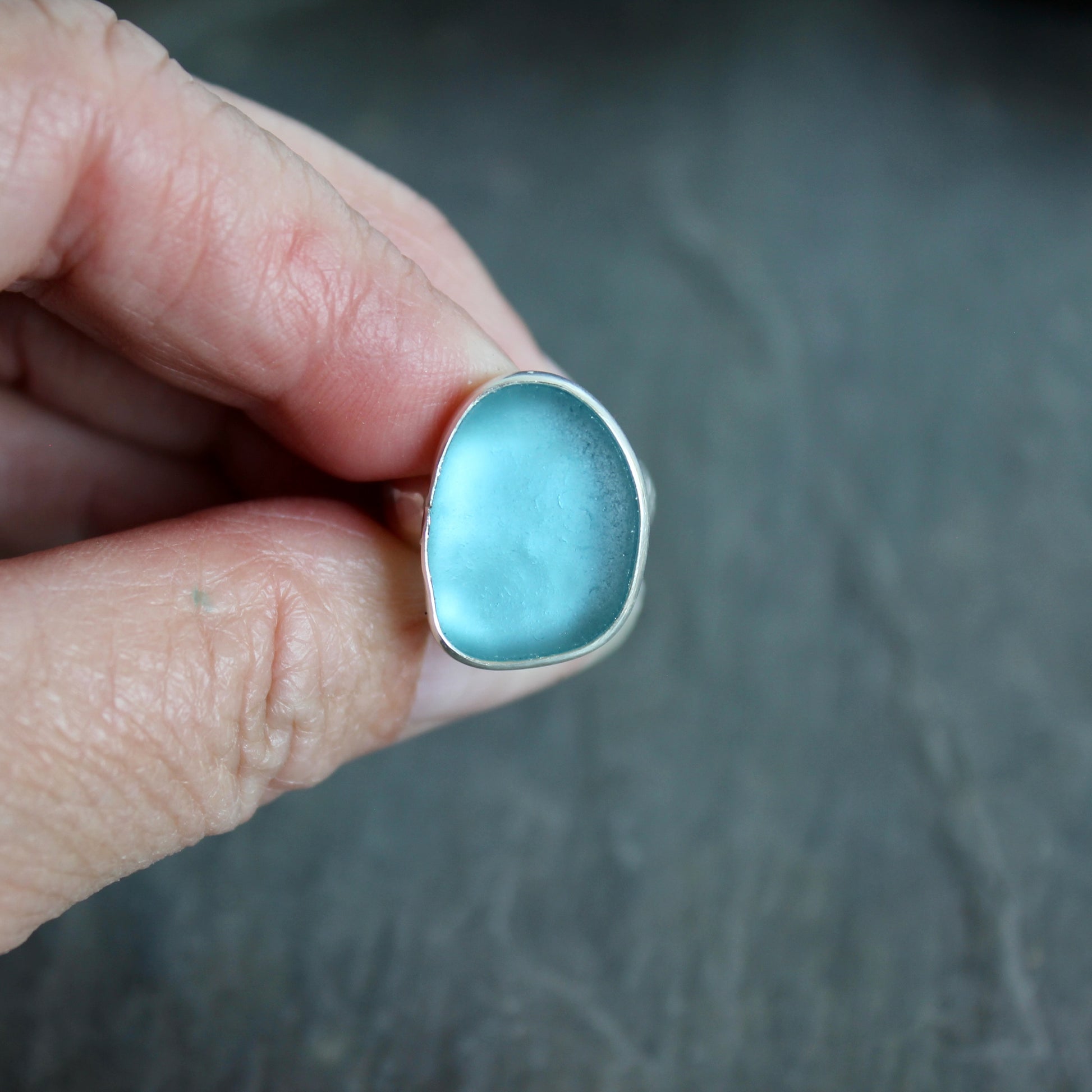 This ring has a large piece of aqua turquoise blue sea glass that is set in a fine and sterling silver bezel setting on a sturdy wide hammered band.  Size 4 1/2 Handmade by Barb Macy in Corvallis, Oregon.