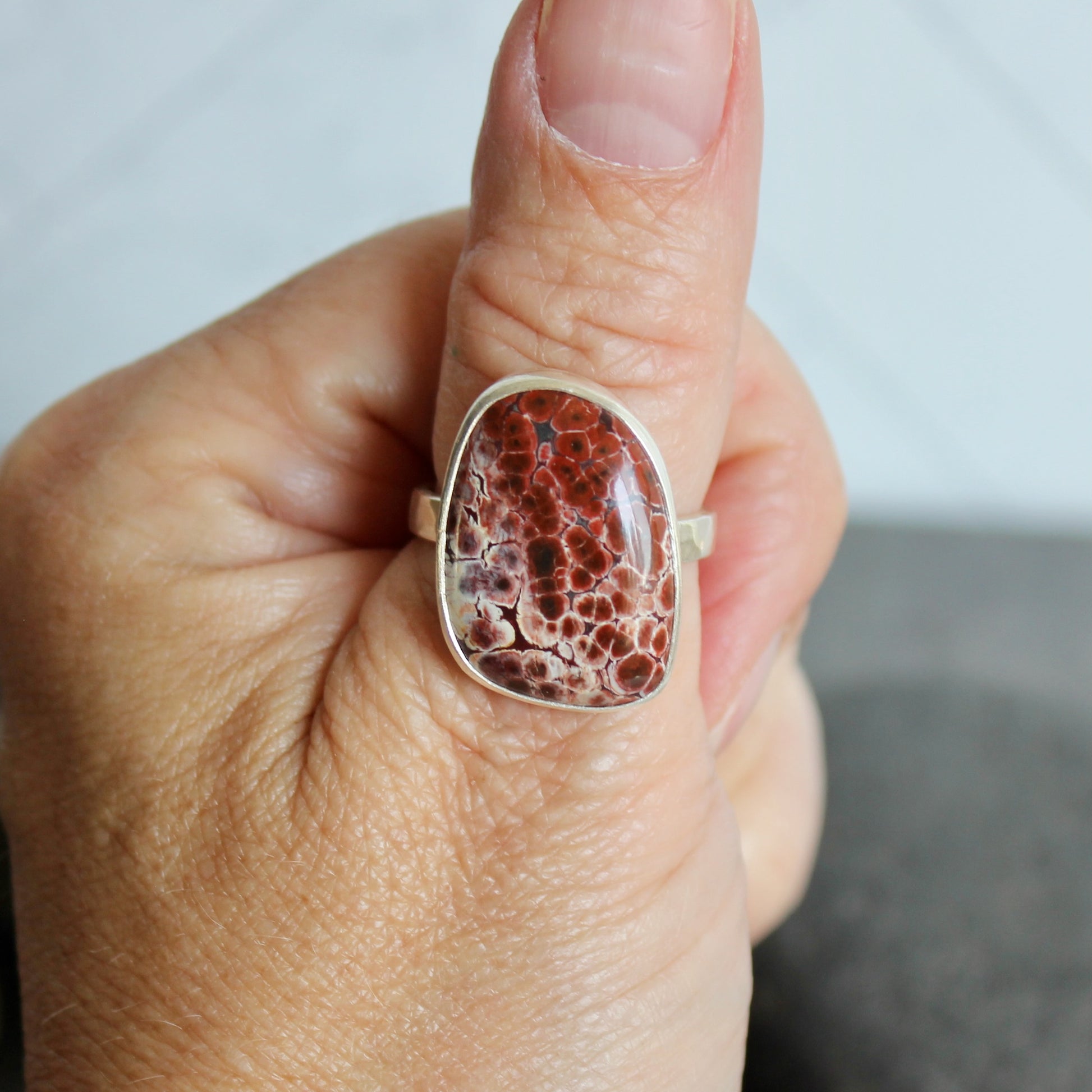 This pretty ring has a locally-sourced red Oregon orbicular jasper that is set in a fine and sterling silver bezel and on a sturdy silver hammered band. Handmade by Will Macy in Corvallis, OR.