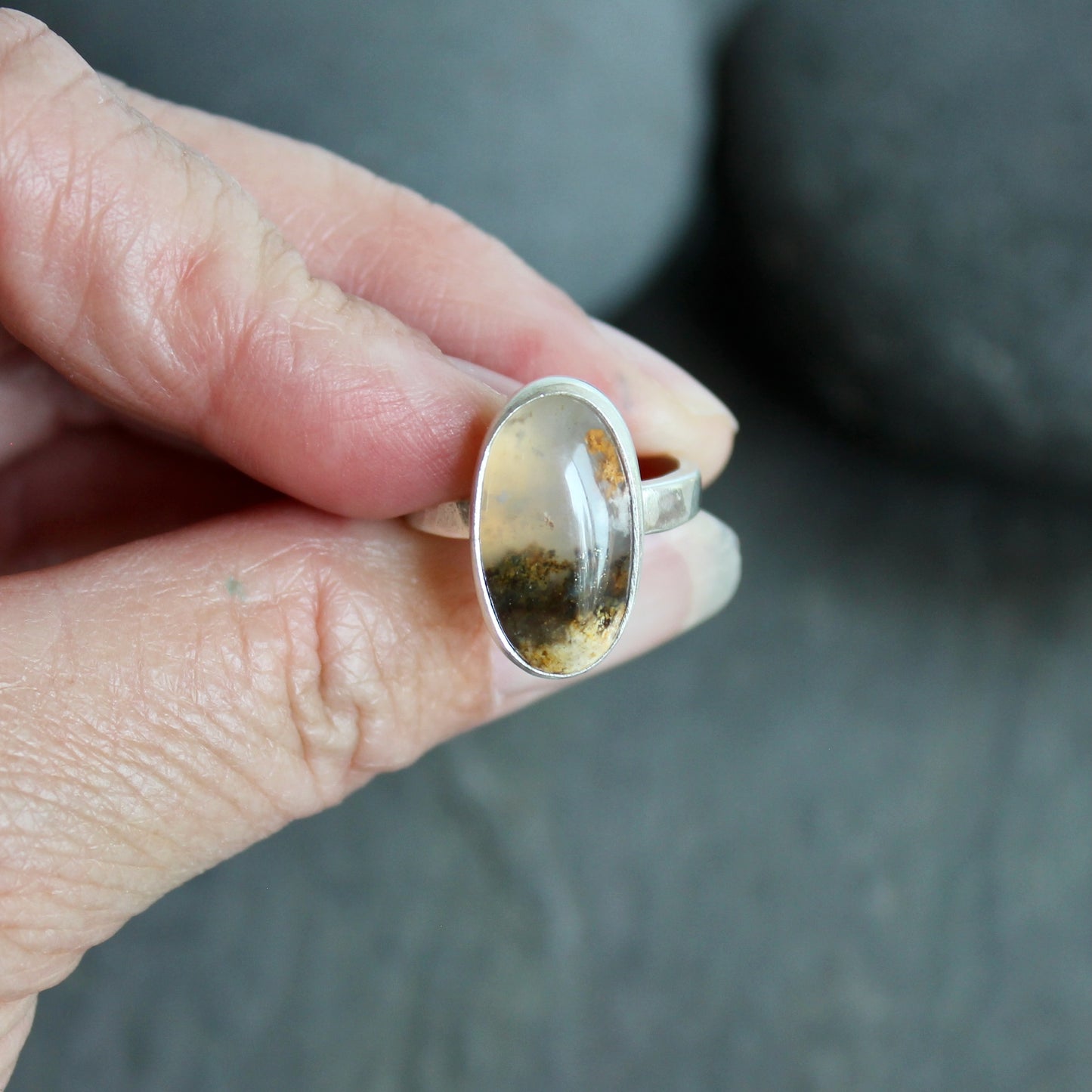 This ring has an Oregon Graveyard Point plume agate that is set in a fine and sterling silver bezel setting on a sturdy hammered band. Size 7 Handmade by Will Macy in Corvallis, Oregon.