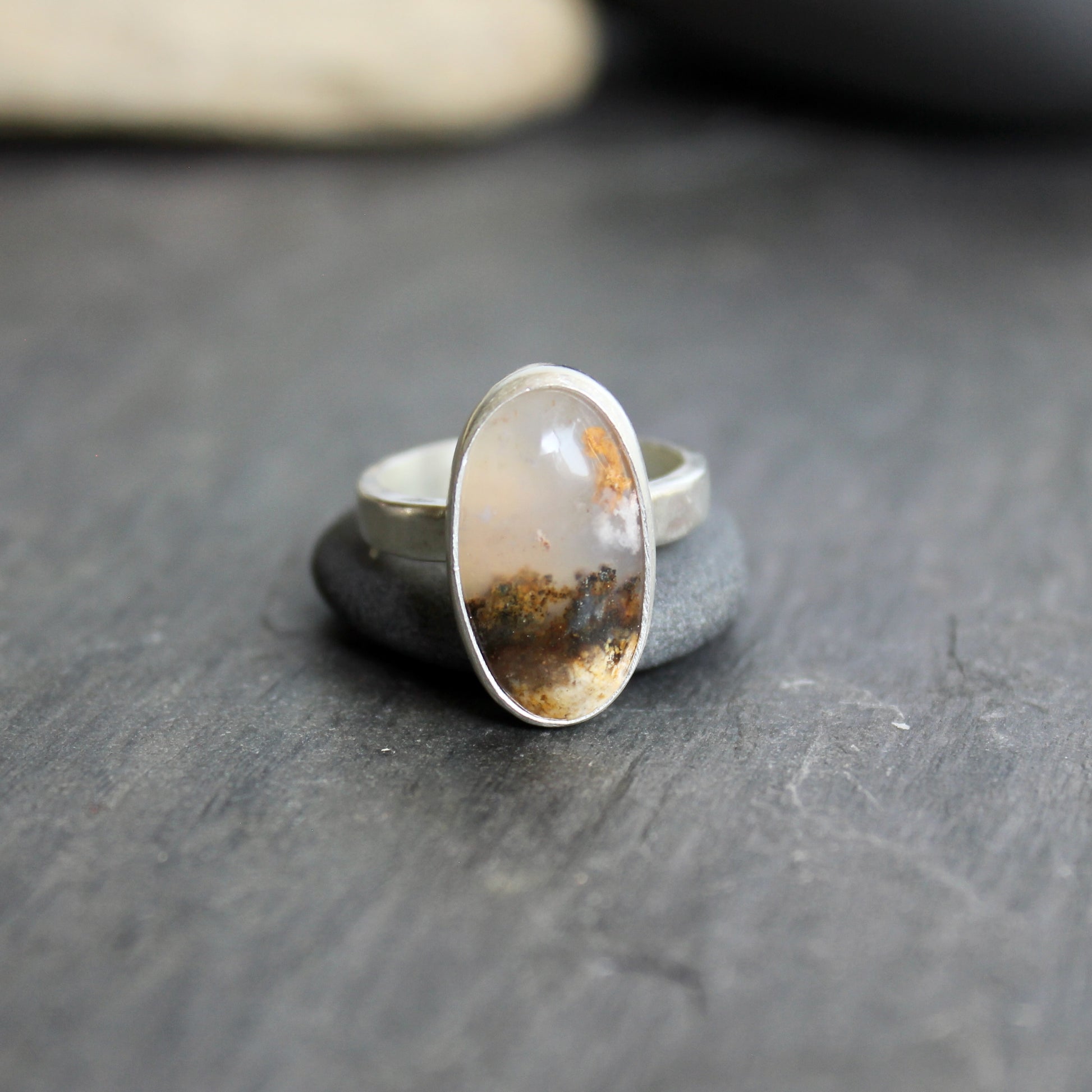 This ring has an Oregon Graveyard Point plume agate that is set in a fine and sterling silver bezel setting on a sturdy hammered band. Size 7 Handmade by Will Macy in Corvallis, Oregon.