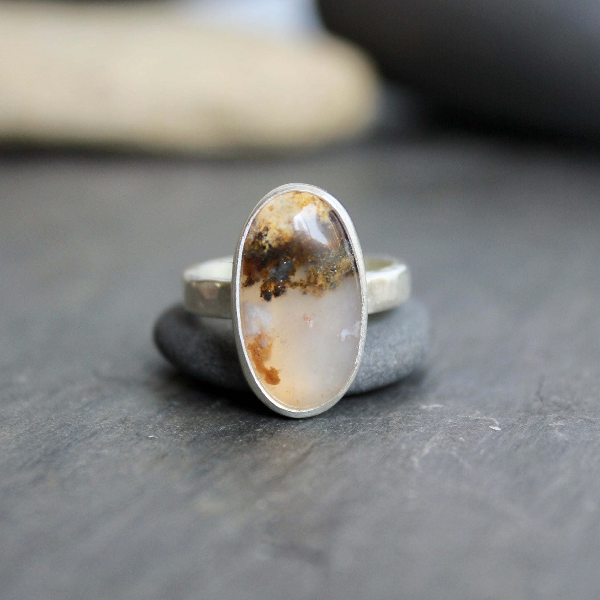 This ring has an Oregon Graveyard Point plume agate that is set in a fine and sterling silver bezel setting on a sturdy hammered band. Size 7 Handmade by Will Macy in Corvallis, Oregon.