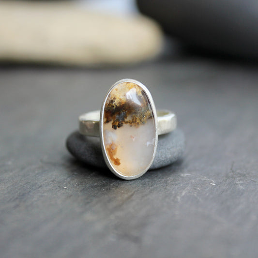 This ring has an Oregon Graveyard Point plume agate that is set in a fine and sterling silver bezel setting on a sturdy hammered band. Size 7 Handmade by Will Macy in Corvallis, Oregon.