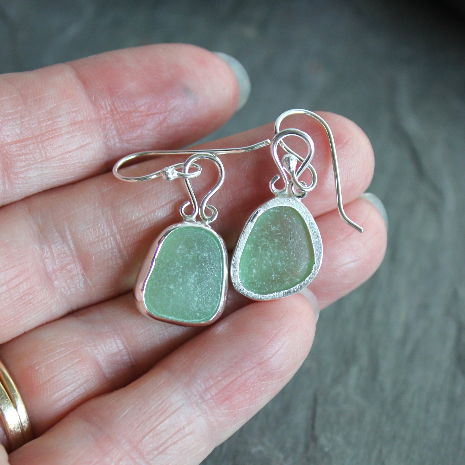 These earrings have two pieces of mint sea foam green sea glass from Massachusetts (USA). They are set in a sterling and fine silver bezel setting and are on sterling silver ear wires. All of our sea glass is found and not altered in any way. Handmade by Barb Macy in Corvallis, OR. 
