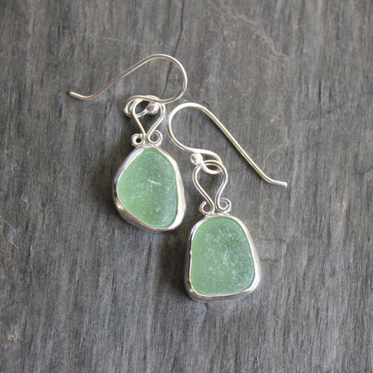 These earrings have two pieces of mint sea foam green sea glass from Massachusetts (USA). They are set in a sterling and fine silver bezel setting and are on sterling silver ear wires. All of our sea glass is found and not altered in any way. Handmade by Barb Macy in Corvallis, OR. 
