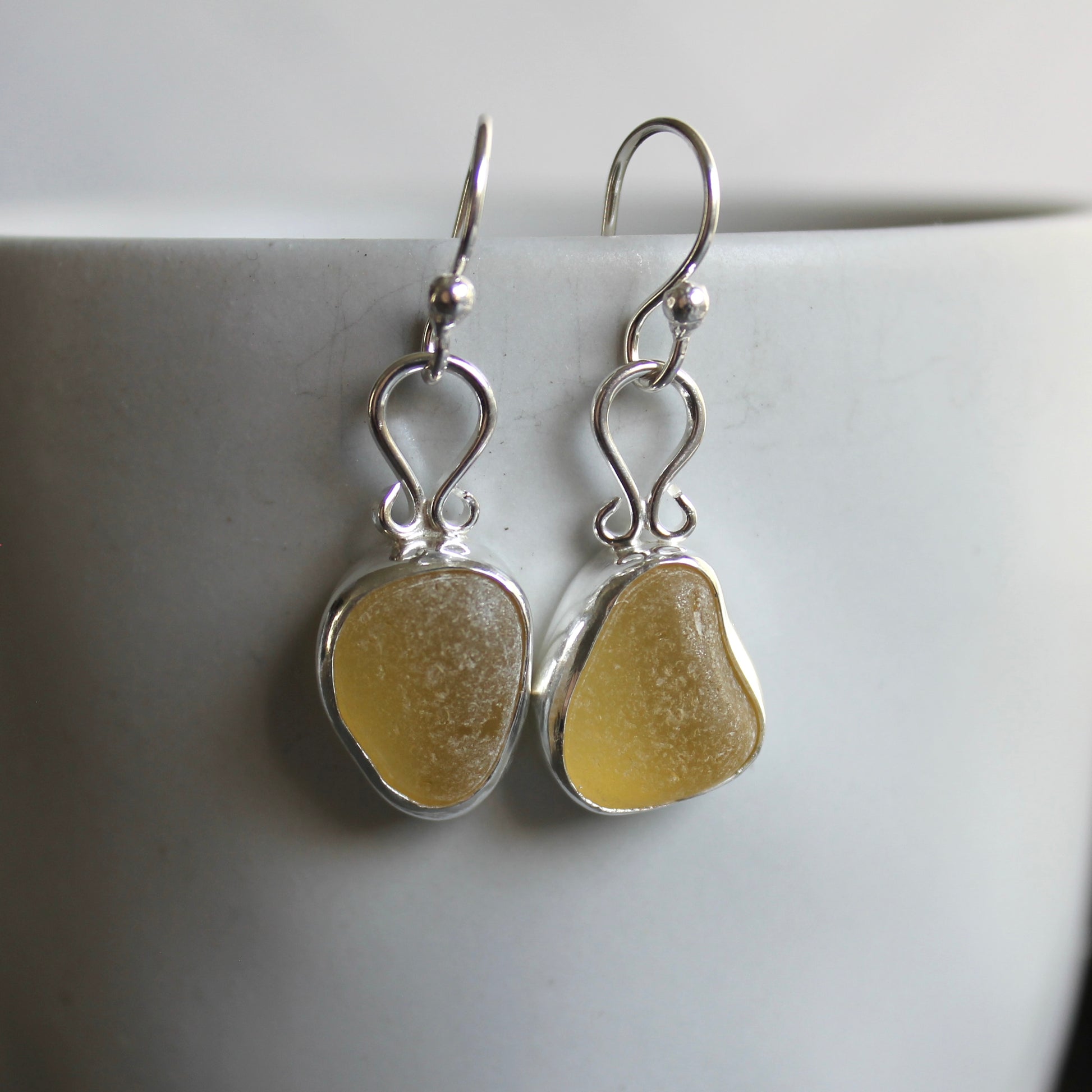 These earrings have two pieces of rare pale yellow sea glass from Massachusetts (USA)... set in sterling and fine silver and attached to handmade sterling silver ear wires. All of our sea glass is found and never altered in any way. All of our sea glass jewelry is handmade by Barb Macy in Corvallis, OR.
