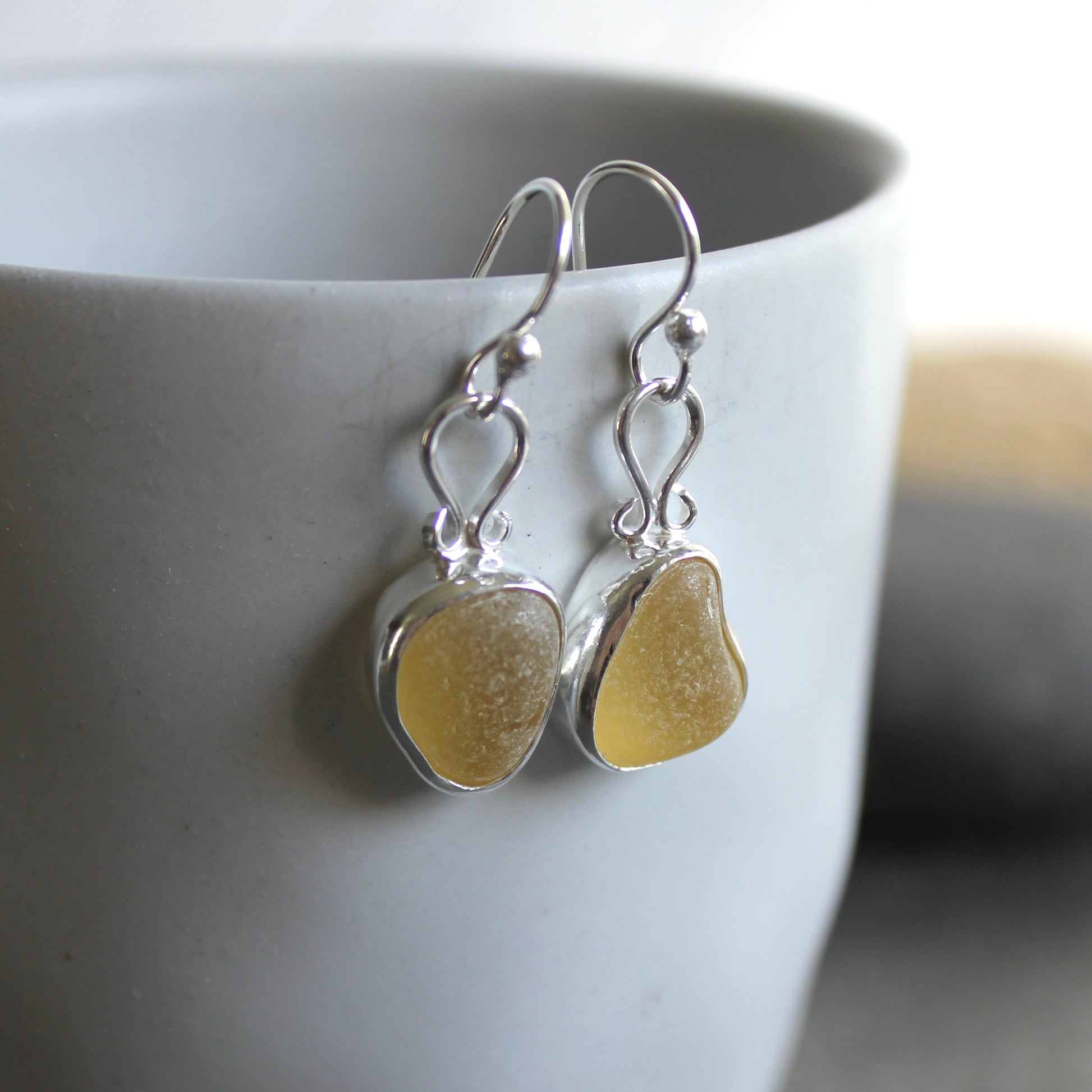 These earrings have two pieces of rare pale yellow sea glass from Massachusetts (USA)... set in sterling and fine silver and attached to handmade sterling silver ear wires. All of our sea glass is found and never altered in any way. All of our sea glass jewelry is handmade by Barb Macy in Corvallis, OR.
