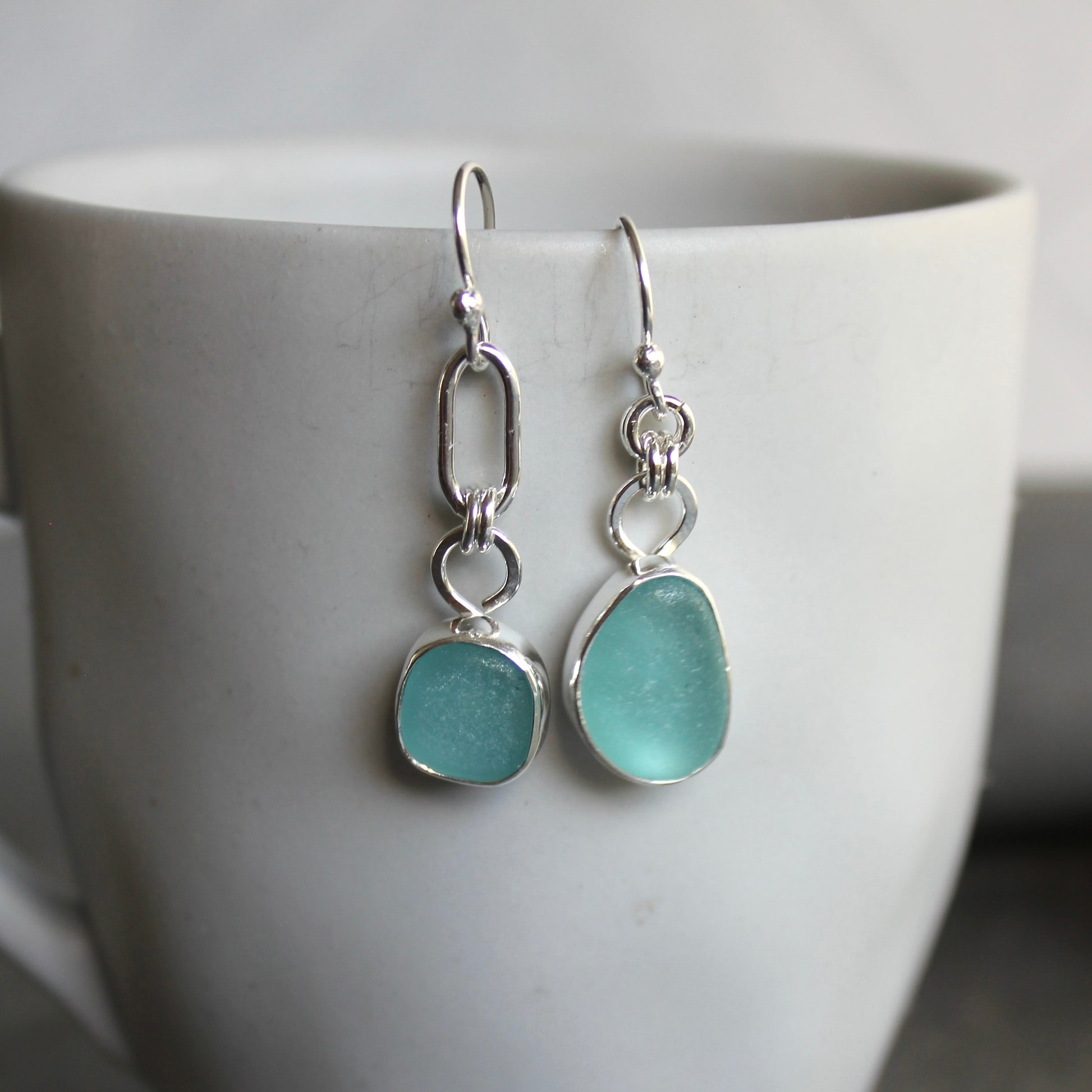 Mismatched Turquoise Blue Sea Glass dangly earrings. They are set in a sterling and fine silver bezel setting and are on sterling silver ear wires.
