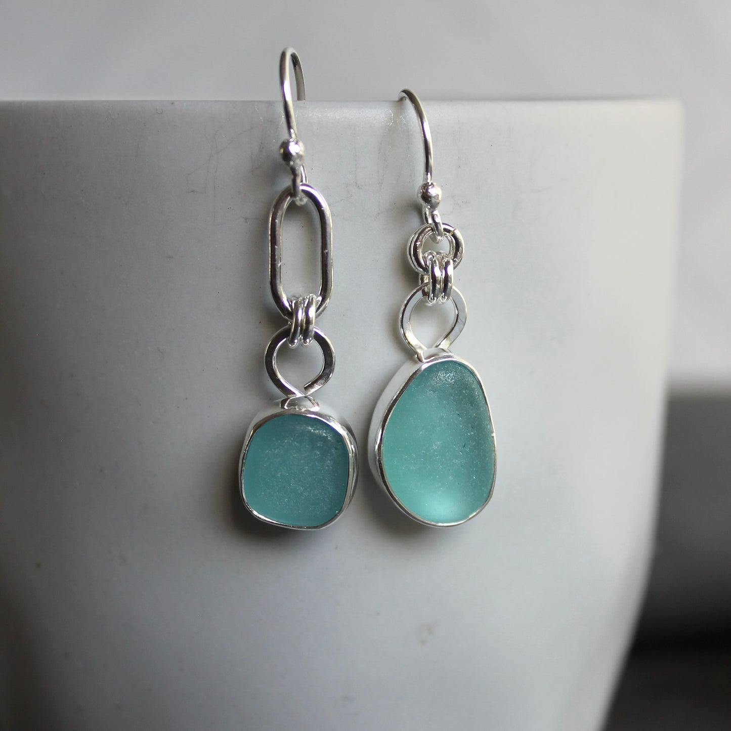 Mismatched Turquoise Blue Sea Glass dangly earrings. They are set in a sterling and fine silver bezel setting and are on sterling silver ear wires.