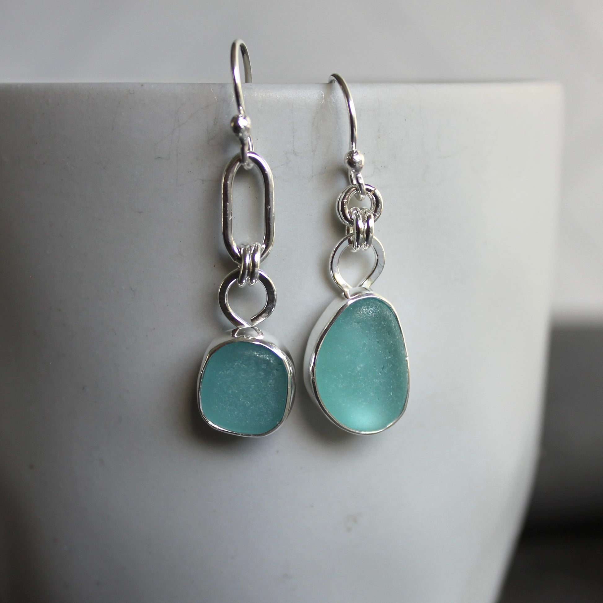 Mismatched Turquoise Blue Sea Glass dangly earrings. They are set in a sterling and fine silver bezel setting and are on sterling silver ear wires.