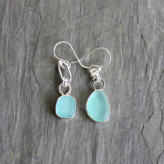 Mismatched Turquoise Blue Sea Glass dangly earrings. They are set in a sterling and fine silver bezel setting and are on sterling silver ear wires.