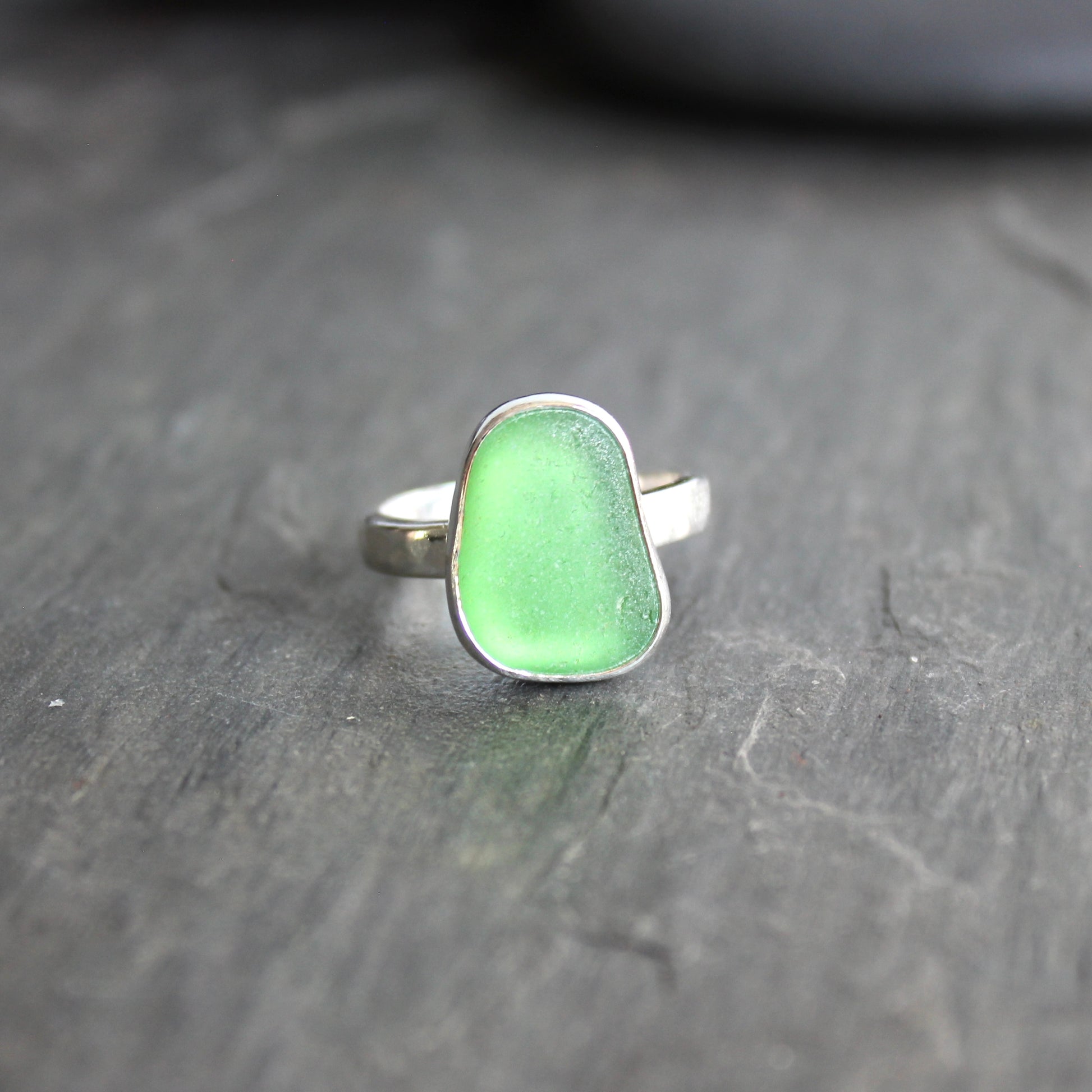 Green ring with silver setting on a dark gray surface