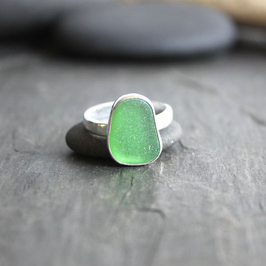 Green sea glass ring on a dark stone surface