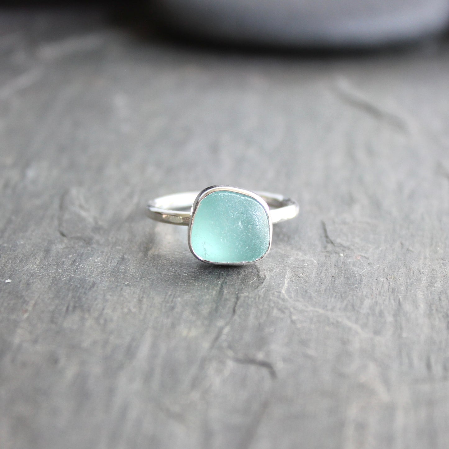 Silver ring with a light blue gemstone on a gray surface