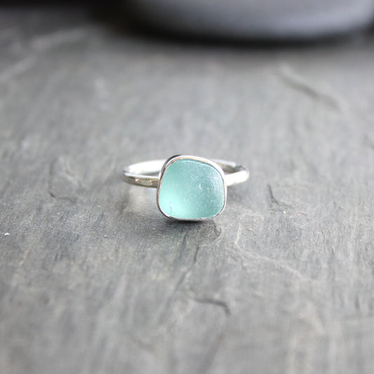 Silver ring with a light blue gemstone on a gray surface