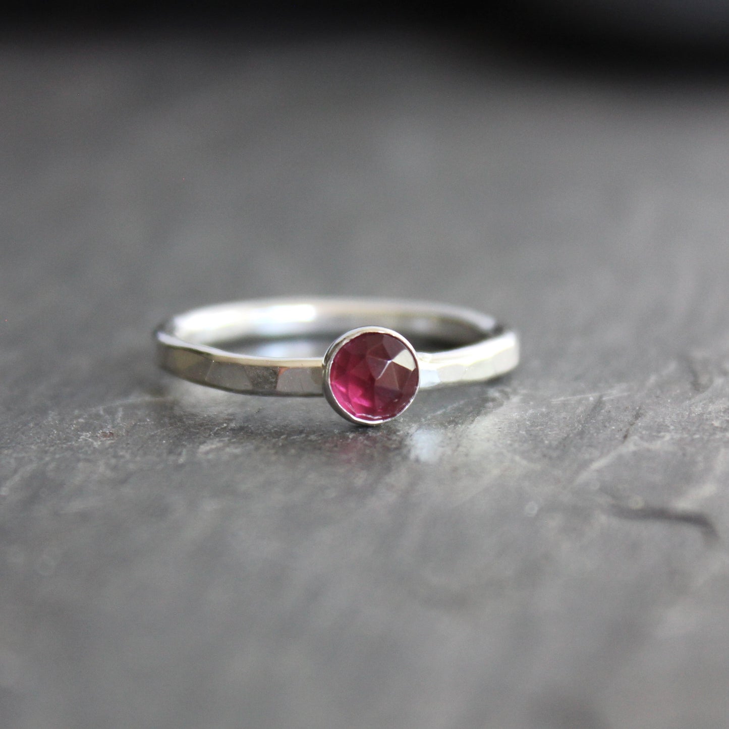 Silver ring with a red gemstone on a dark gray surface