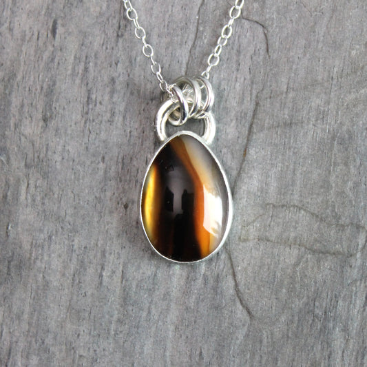 Montana Agate cabochon showing natural banded patterns and inclusions, set in sterling silver pendant