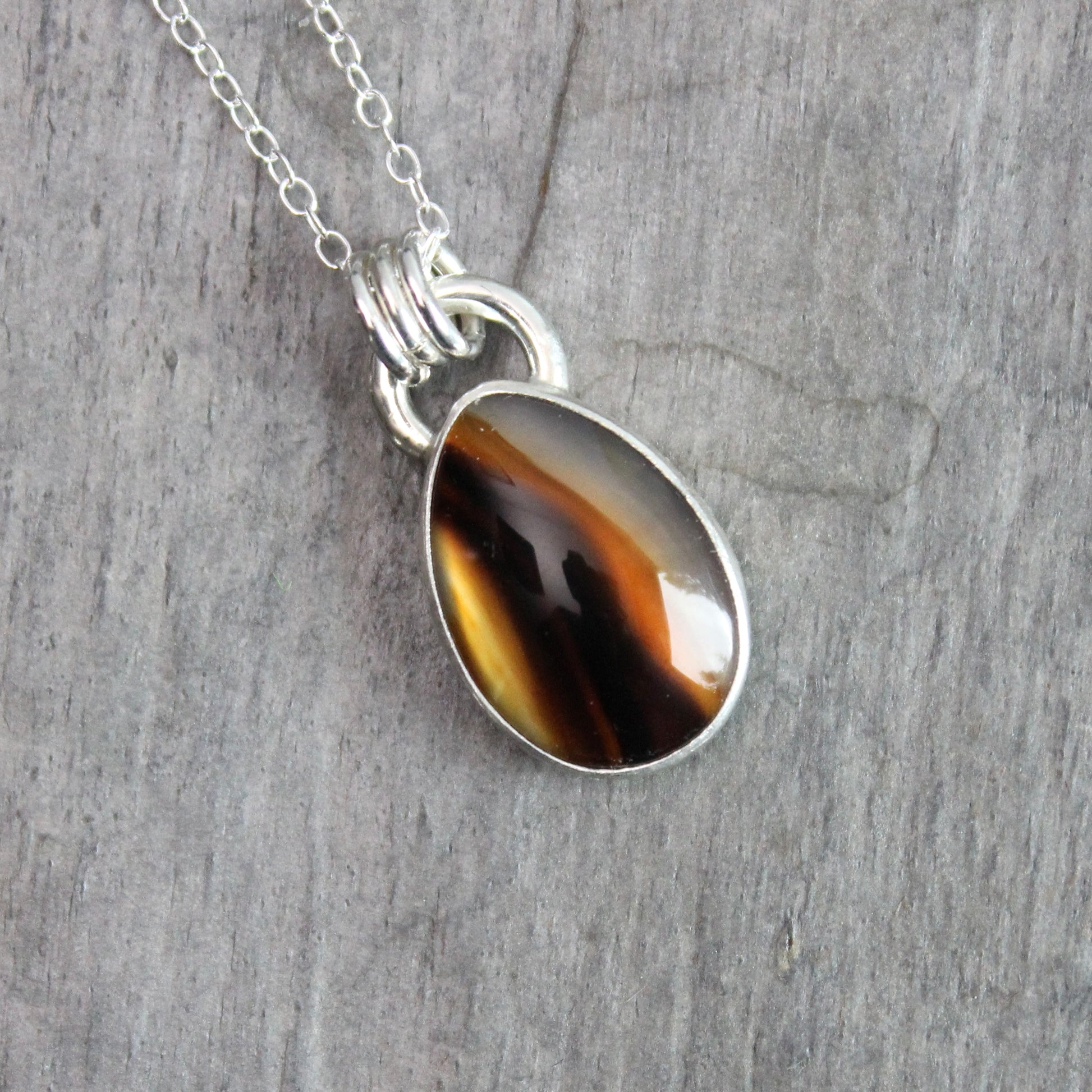 Montana Agate cabochon showing natural banded patterns and inclusions, set in sterling silver pendant