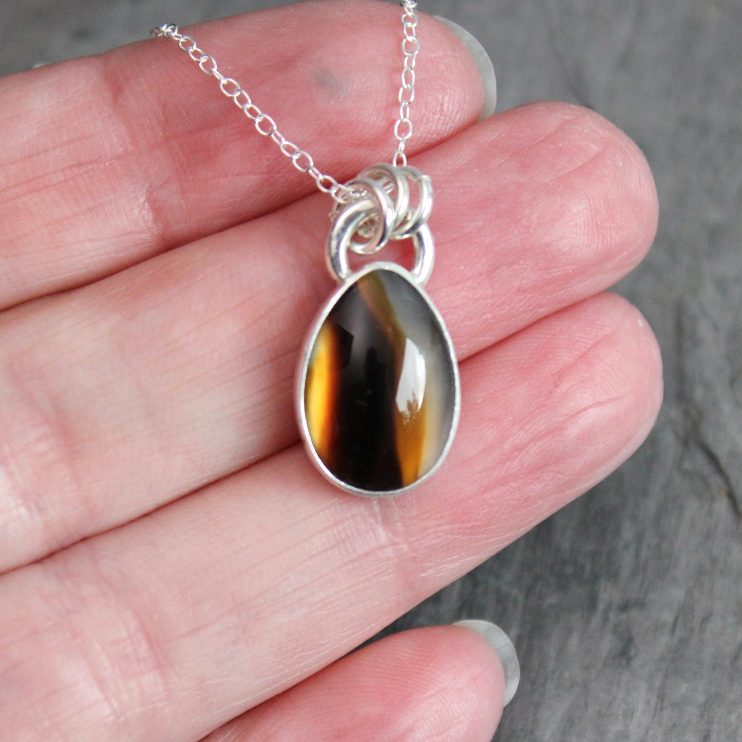 Montana Agate cabochon showing natural banded patterns and inclusions, set in sterling silver pendant