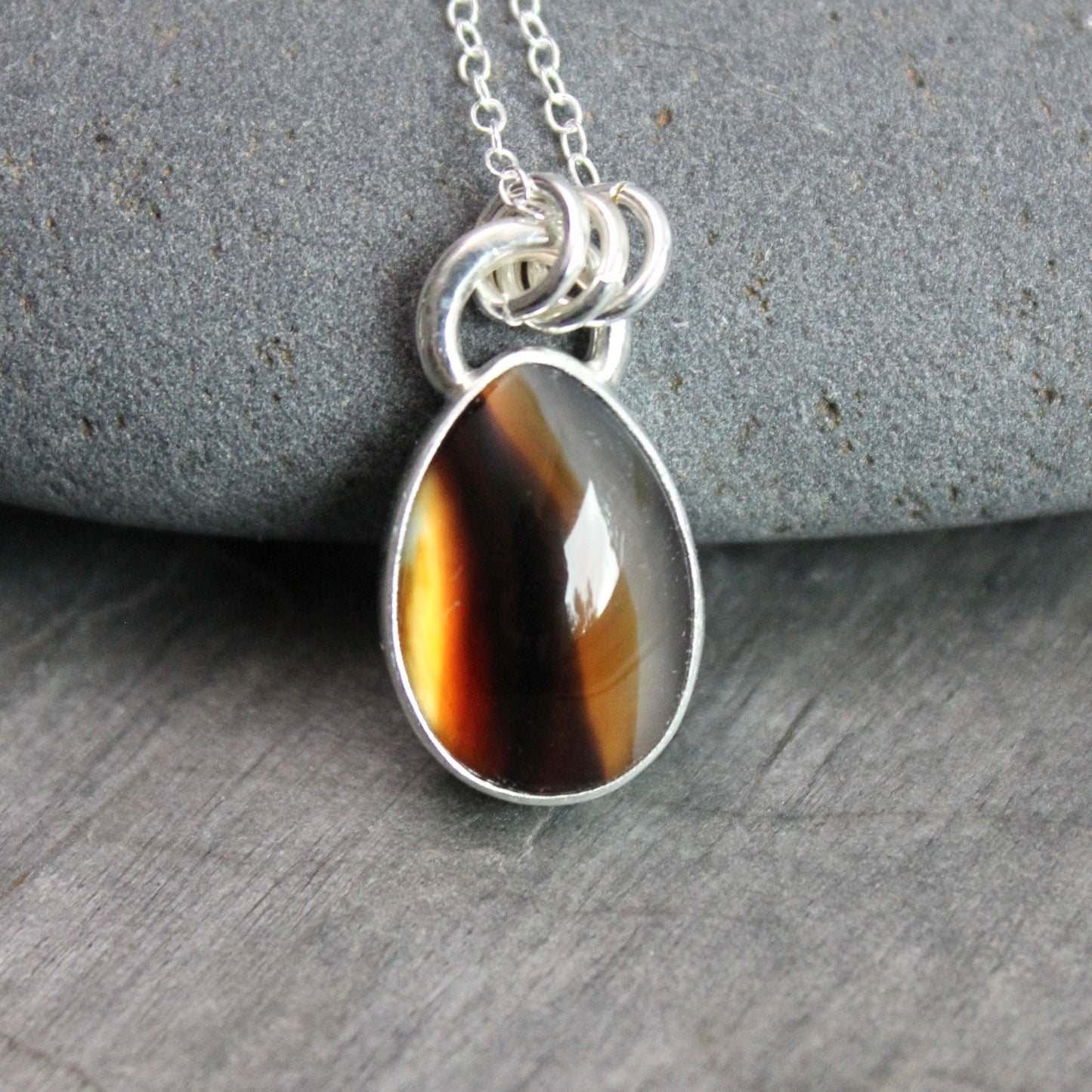 Montana Agate cabochon showing natural banded patterns and inclusions, set in sterling silver pendant