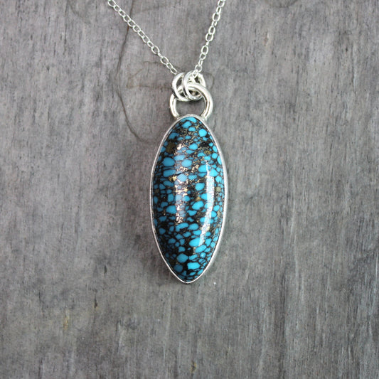 val spider web turquoise with pyrite pendant set in sterling silver with an adjustable silver chain, displayed on a rustic gray slate background.