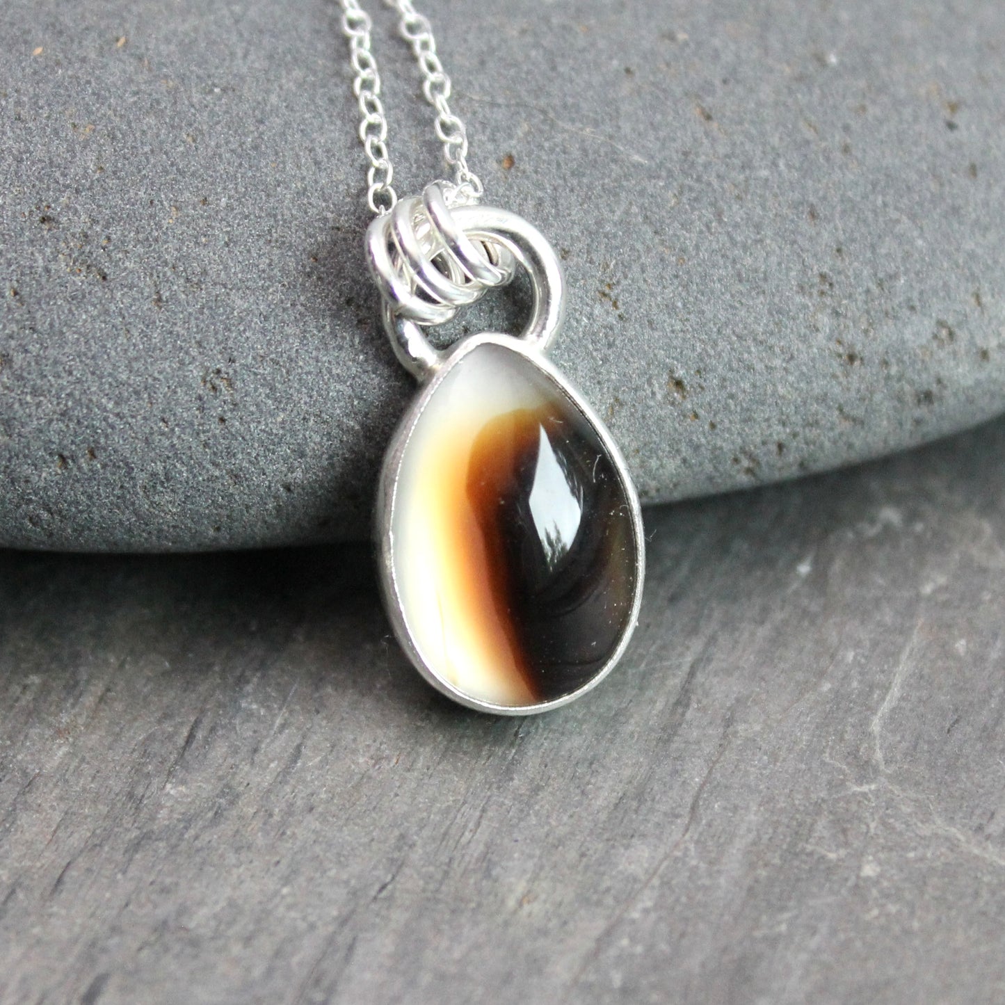 Montana Agate cabochon showing natural banded patterns and inclusions, set in sterling silver pendant