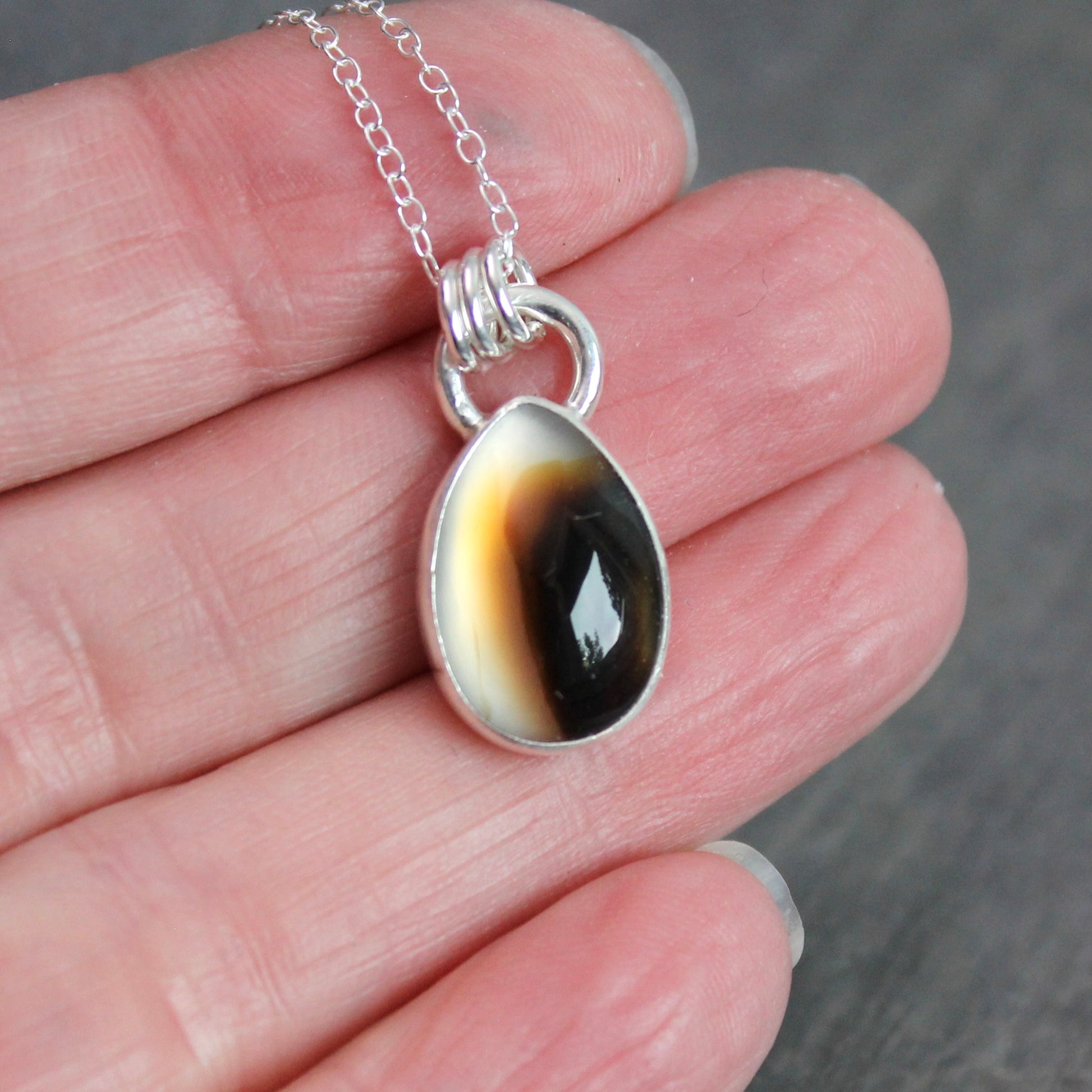 Montana Agate cabochon showing natural banded patterns and inclusions, set in sterling silver pendant