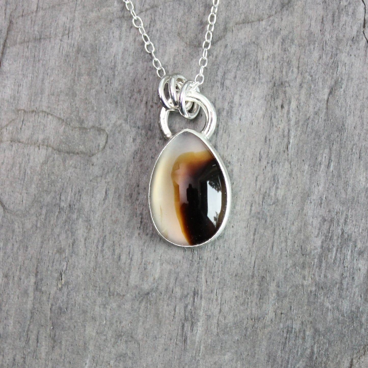 Montana Agate cabochon showing natural banded patterns and inclusions, set in sterling silver pendant