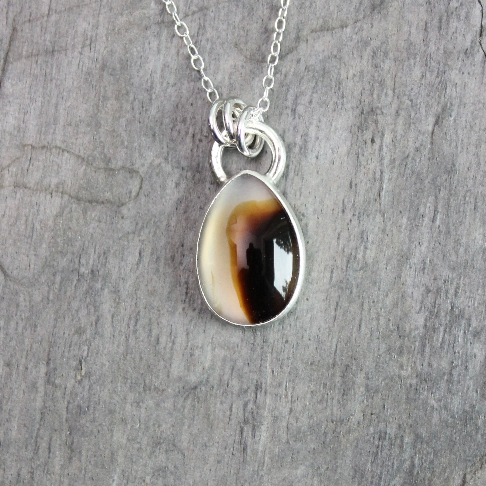 Montana Agate cabochon showing natural banded patterns and inclusions, set in sterling silver pendant