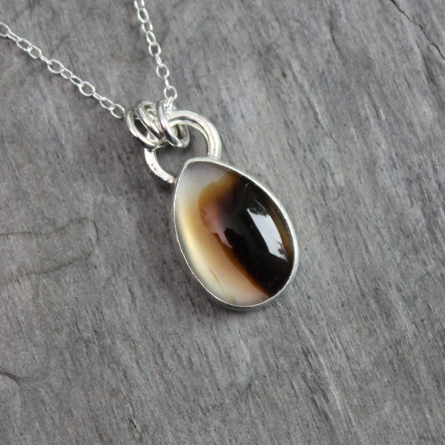 Montana Agate cabochon showing natural banded patterns and inclusions, set in sterling silver pendant