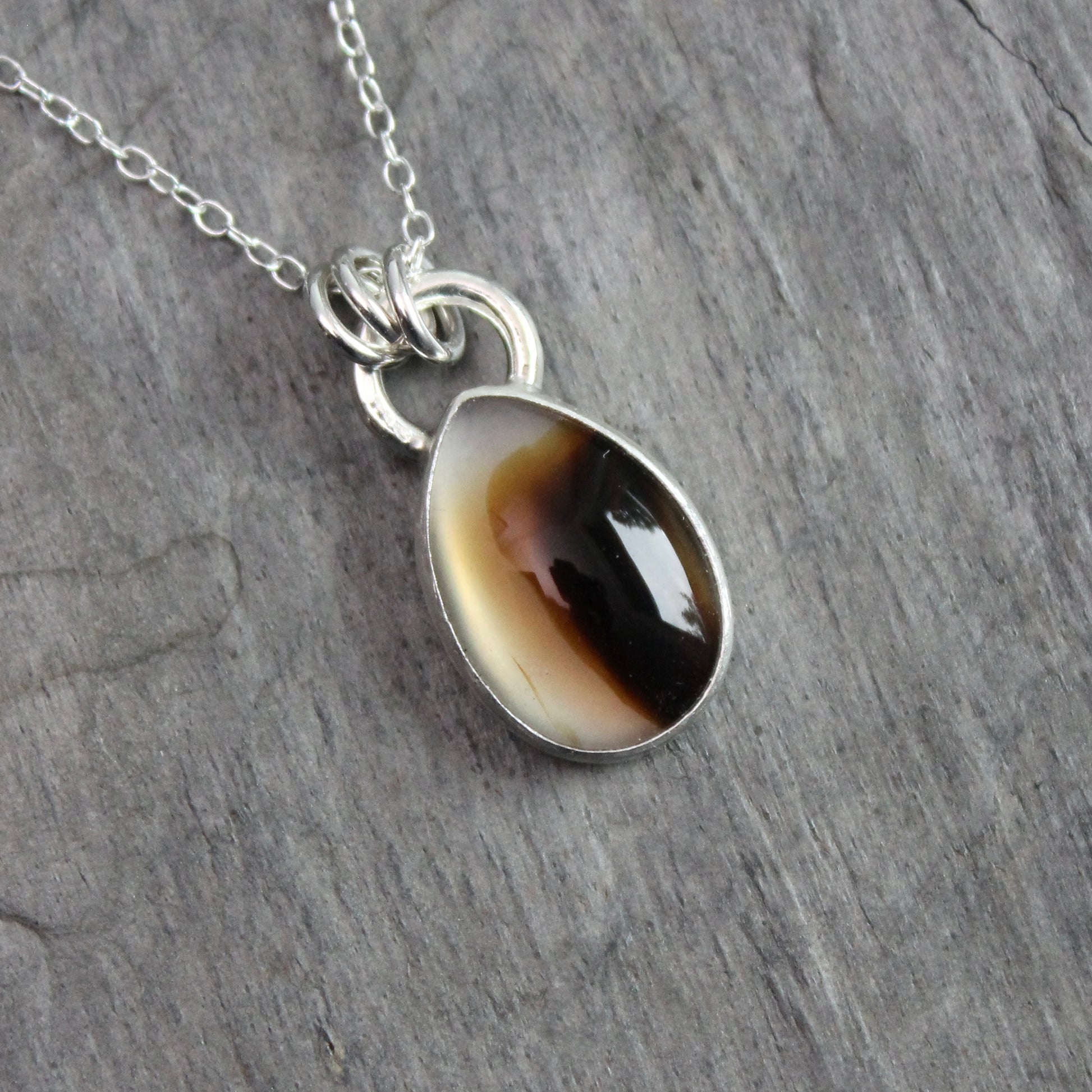 Montana Agate cabochon showing natural banded patterns and inclusions, set in sterling silver pendant