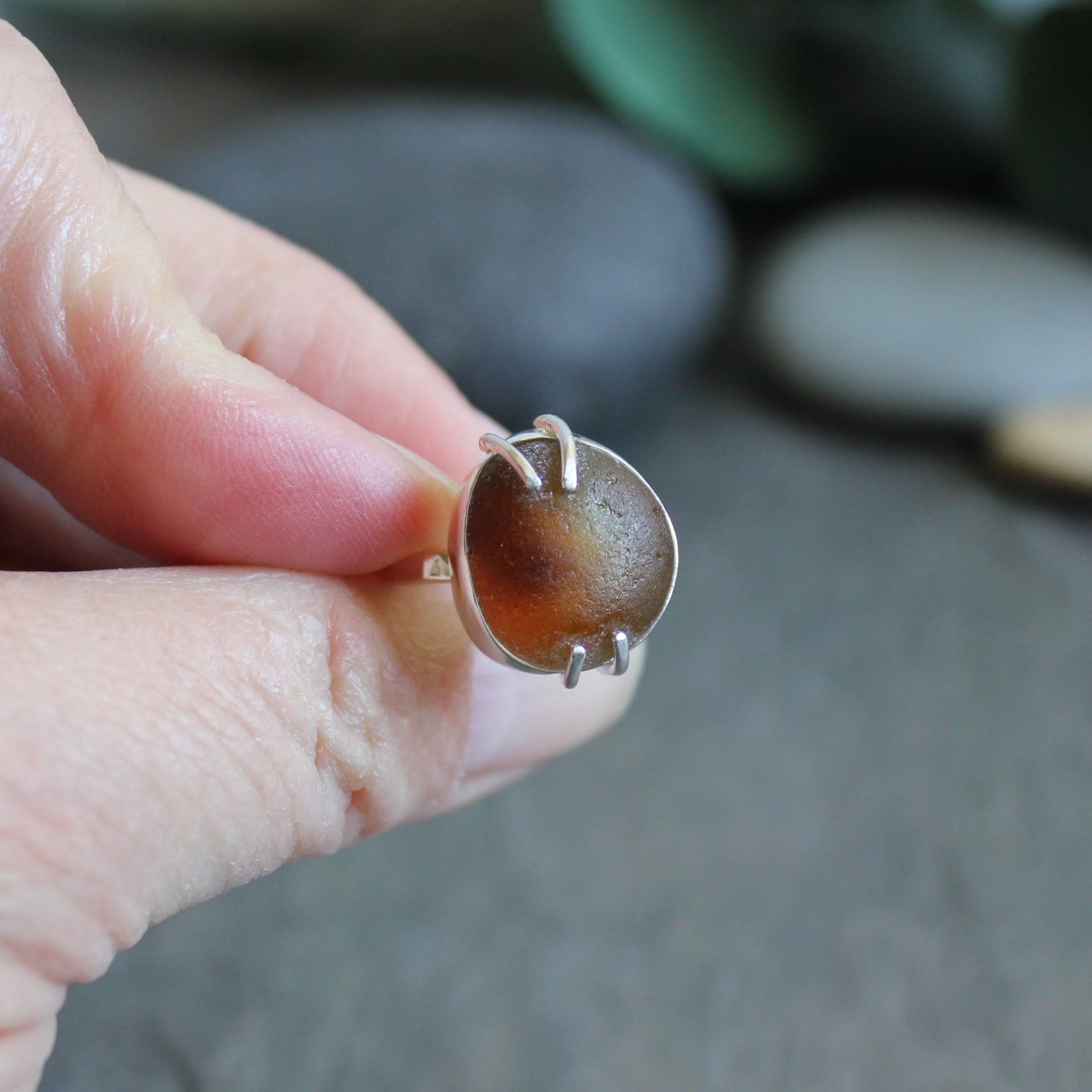 This ring has a piece of amber brown Seaham (UK) sea glass that is set in a fine and sterling silver bezel and soldered to a sturdy sterling silver band.