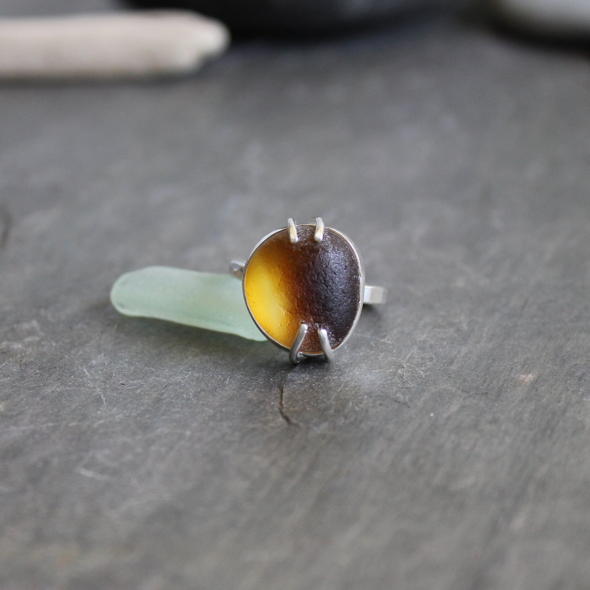 This ring has a piece of amber brown Seaham (UK) sea glass that is set in a fine and sterling silver bezel and soldered to a sturdy sterling silver band.