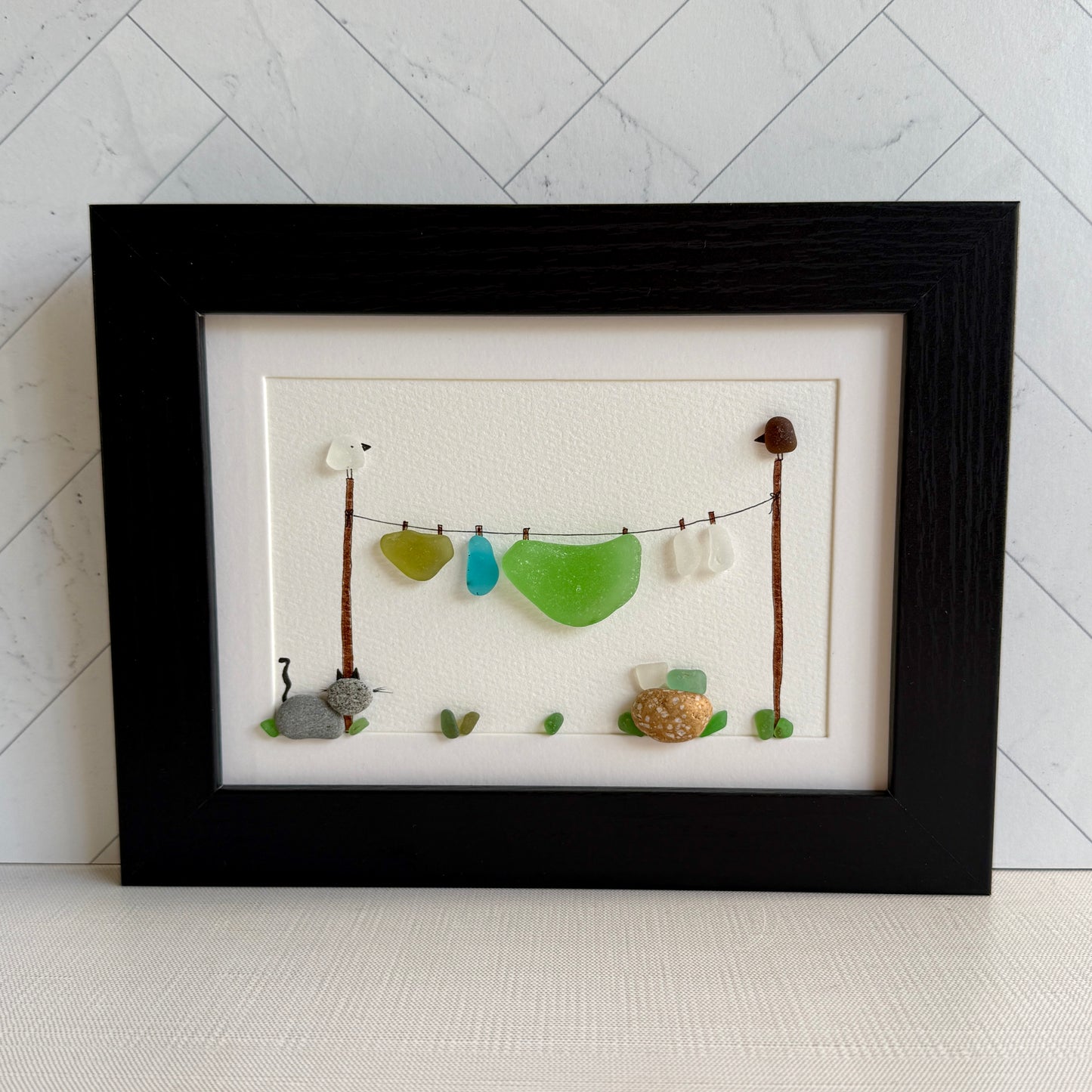Framed artwork with sea glass pieces on a white background