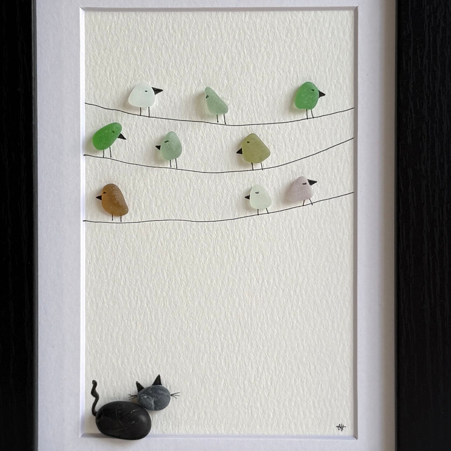 Framed sea glass artwork with birds and a pebble cat on a white background