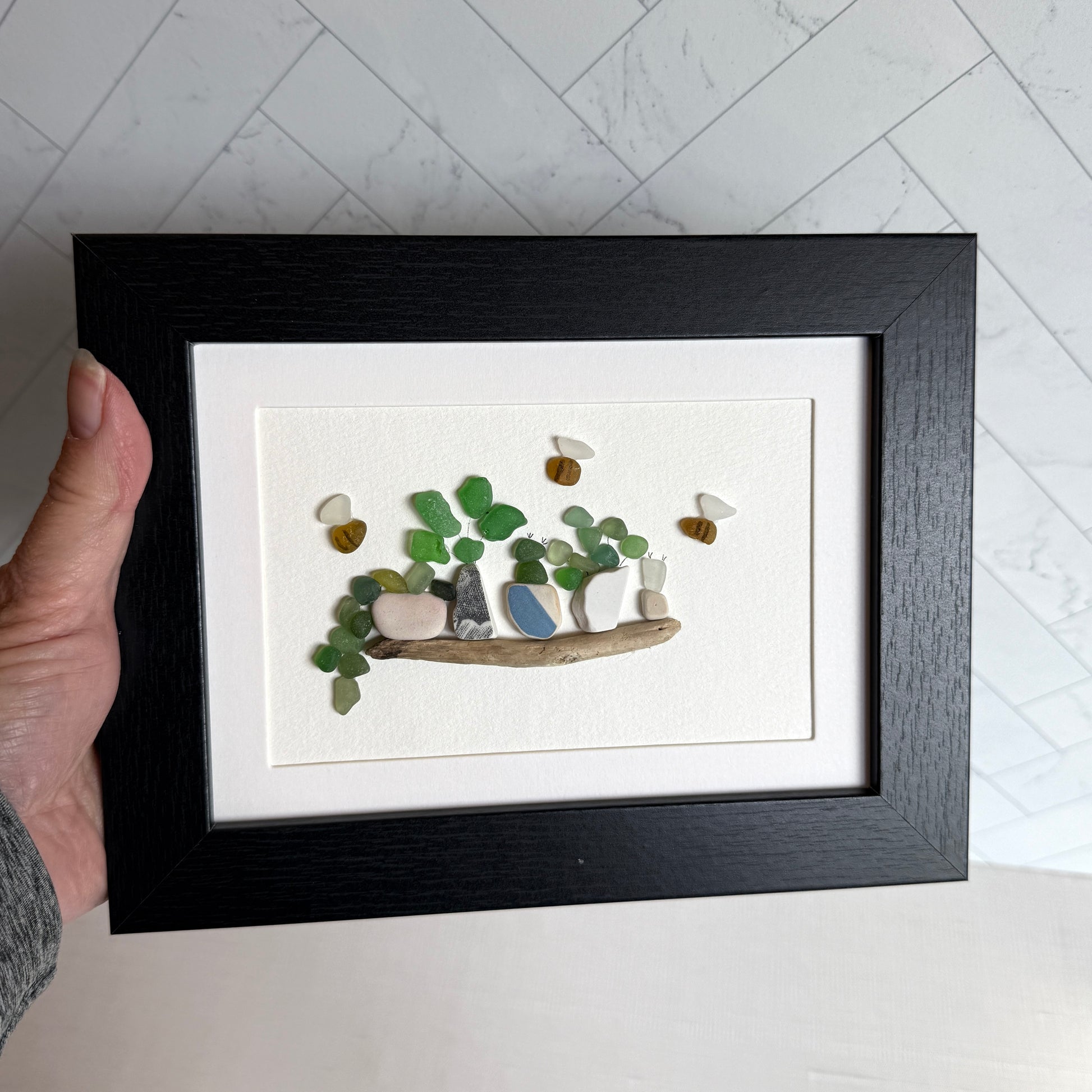Framed artwork with pebbles on a white background