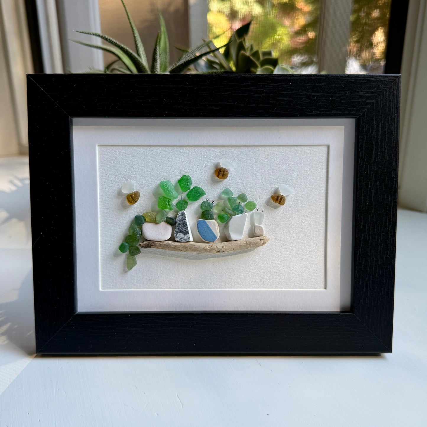 Framed artwork of a small garden scene with pots and plants on a white background