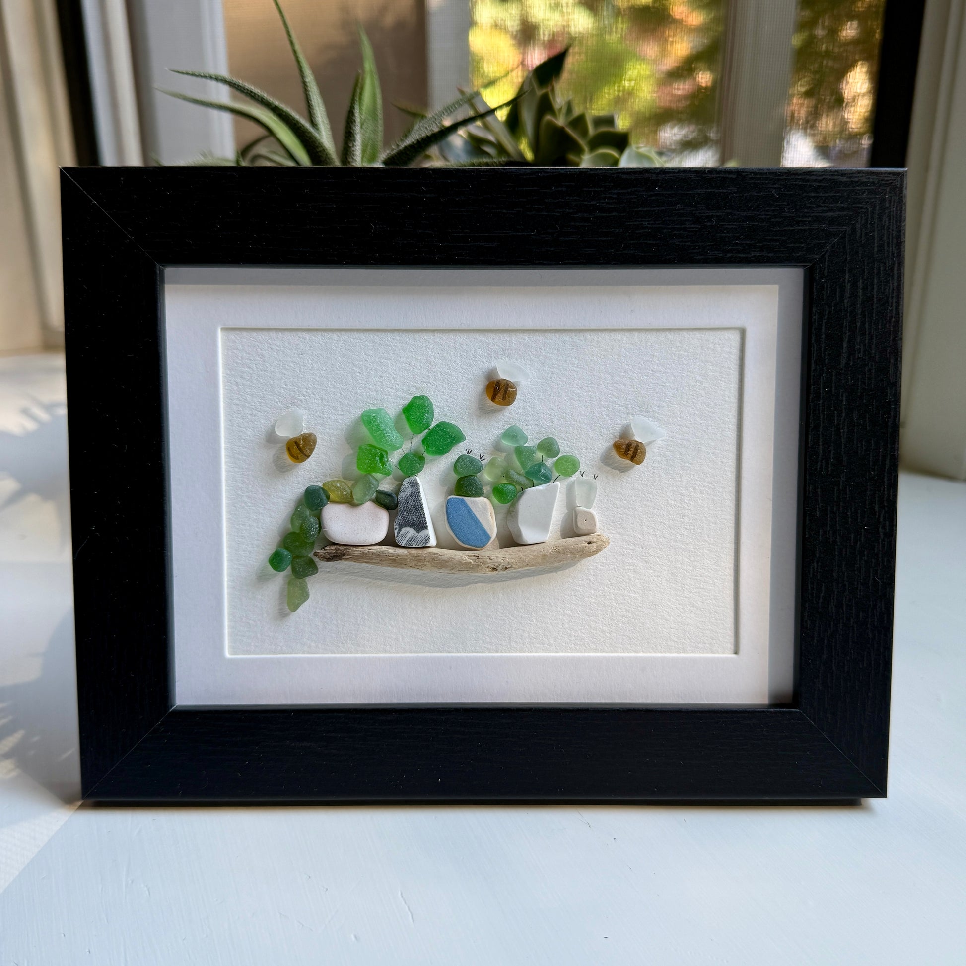 Framed artwork of a small garden scene with pots and plants on a white background