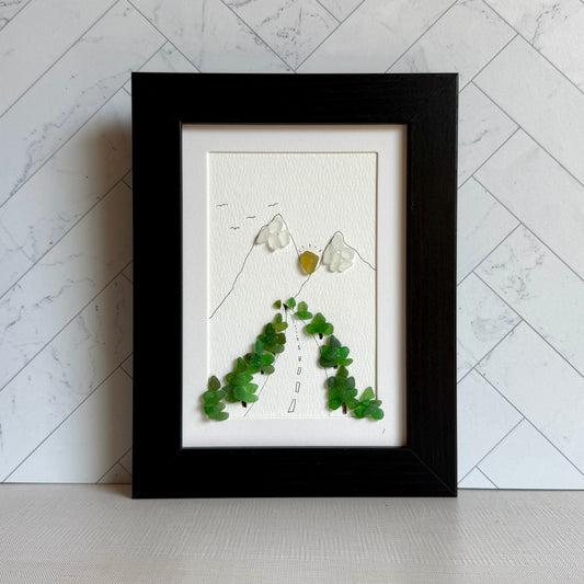 Framed artwork with green leaves and white flowers on a marble wall background