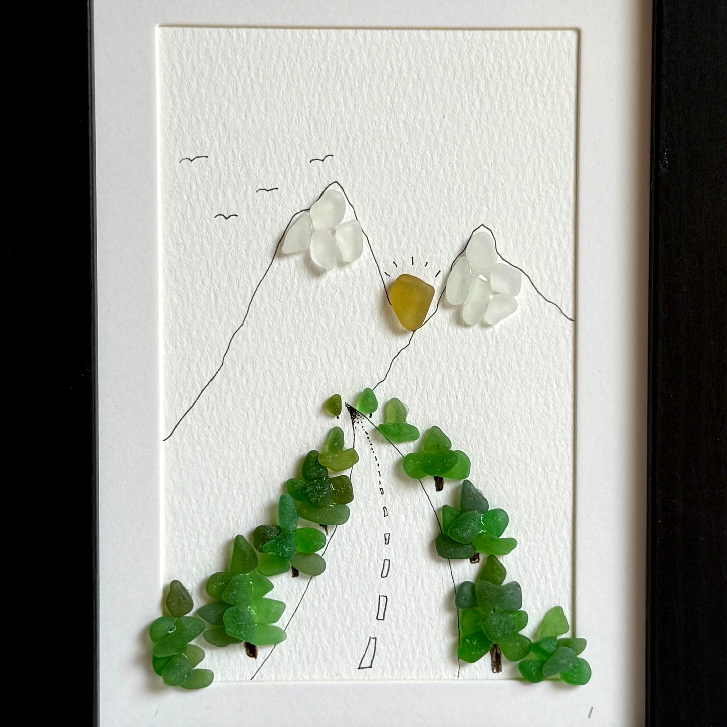 Artistic depiction of a mountain landscape made with green and white stones on a white background