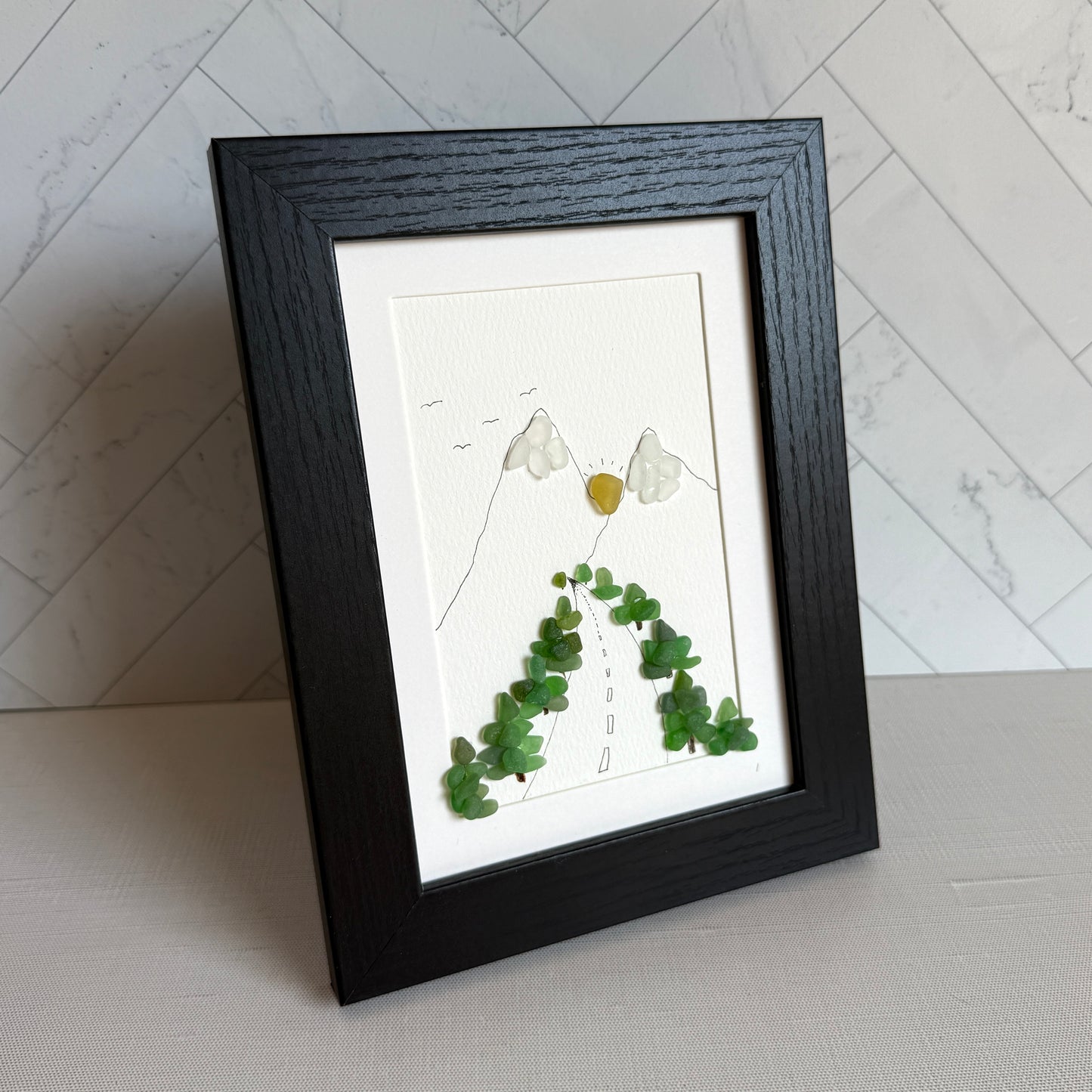 Framed artwork with green leaves on a white background