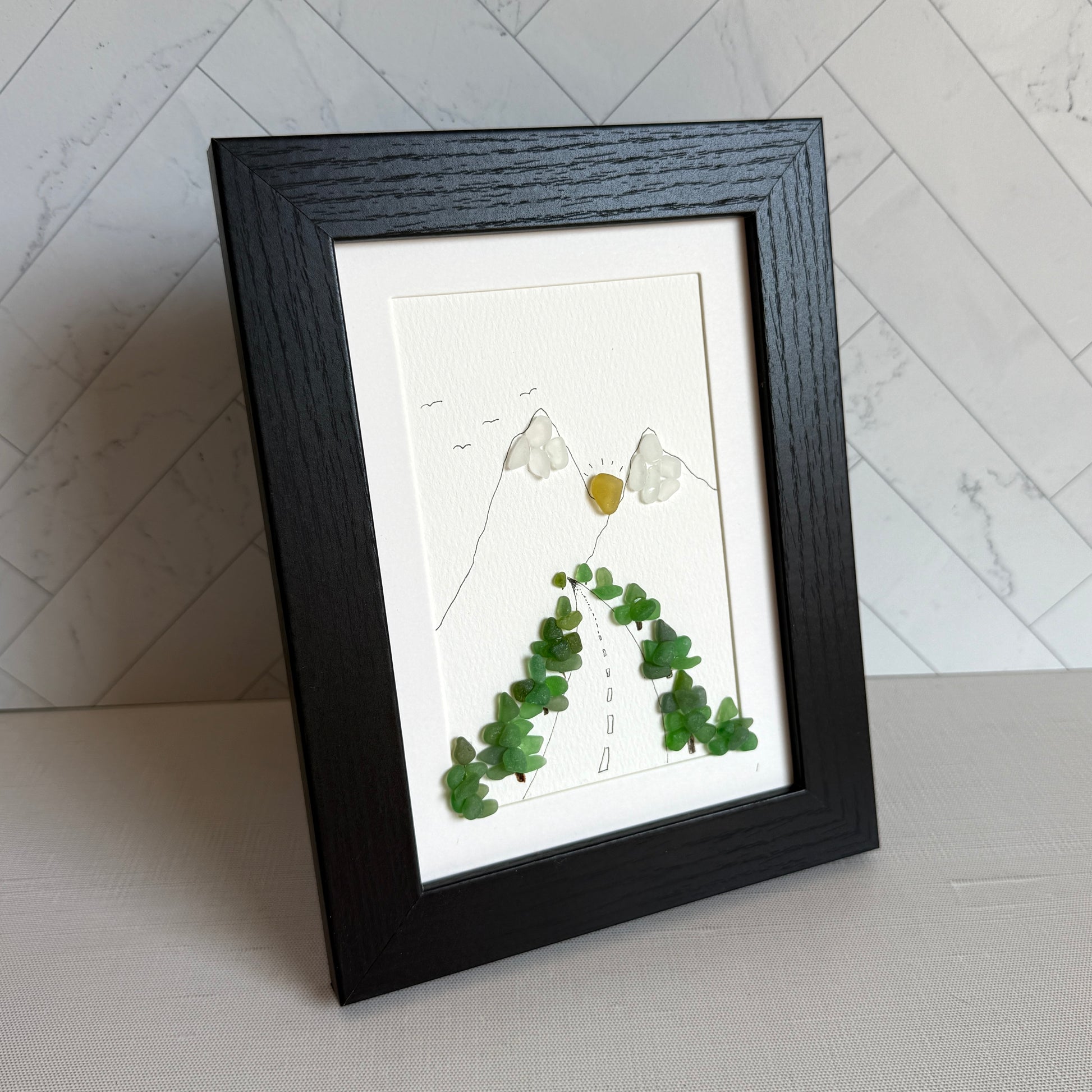 Framed artwork with green leaves on a white background