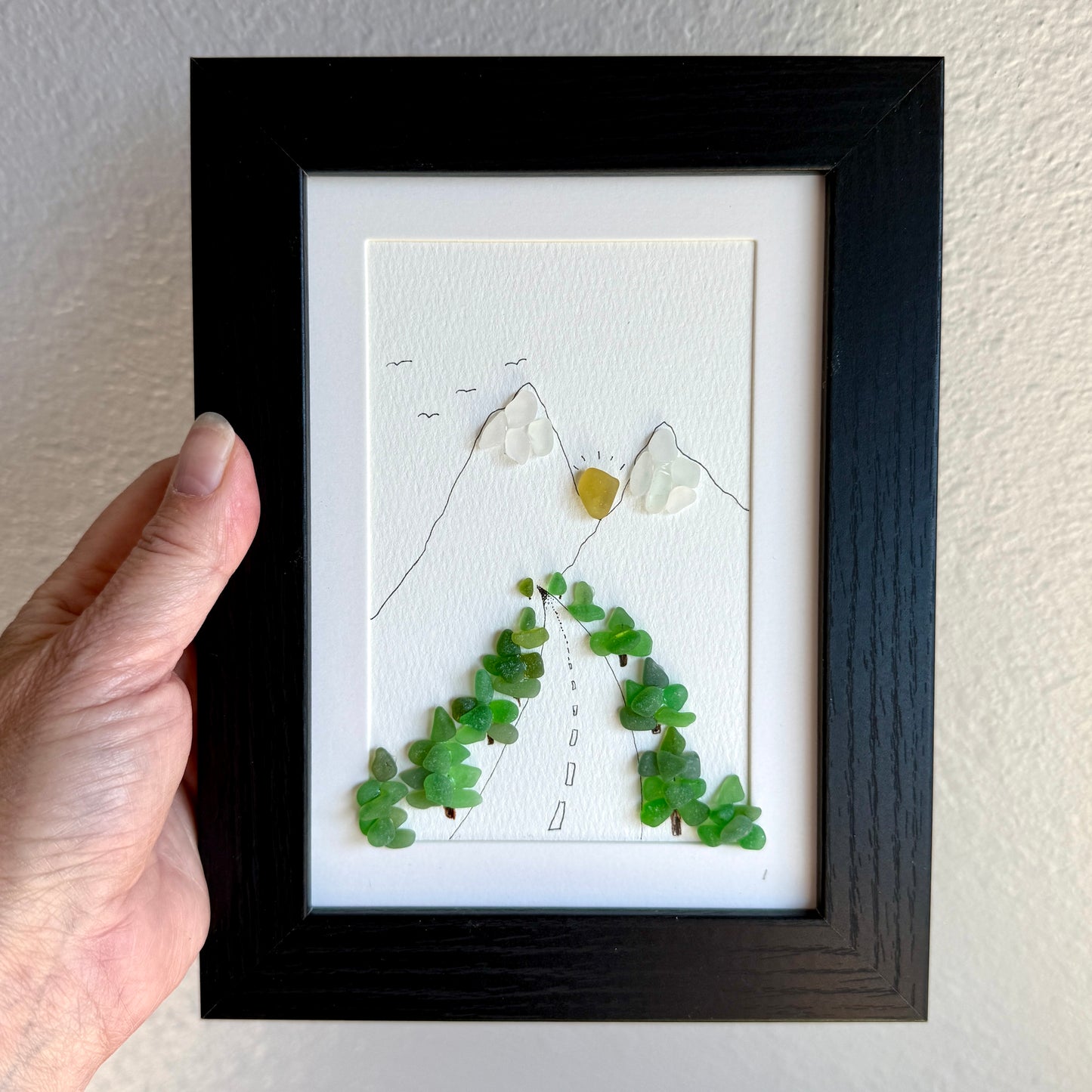 Framed artwork with green leaf-like shapes and a black frame