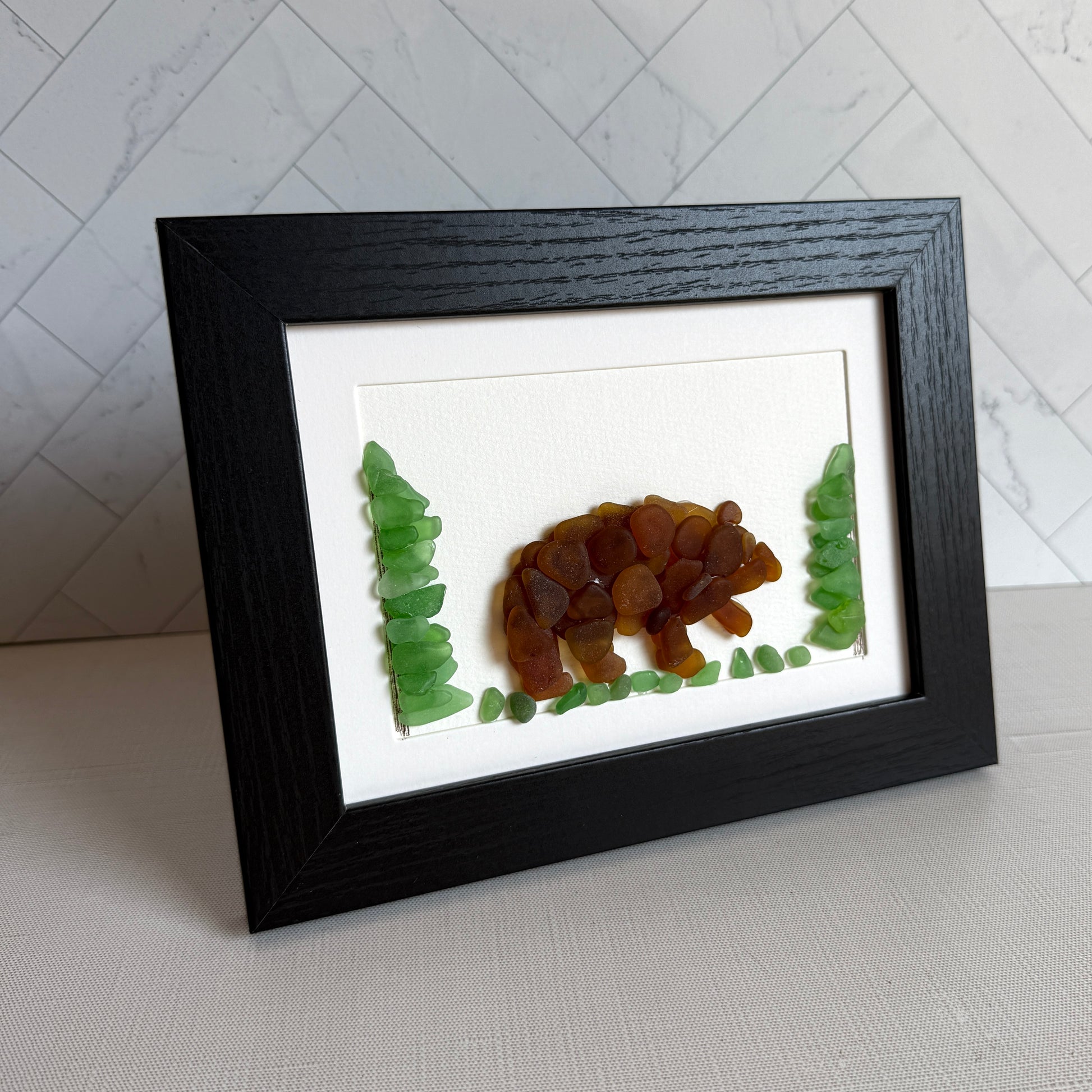 Framed artwork of a bear made from natural materials on a white background