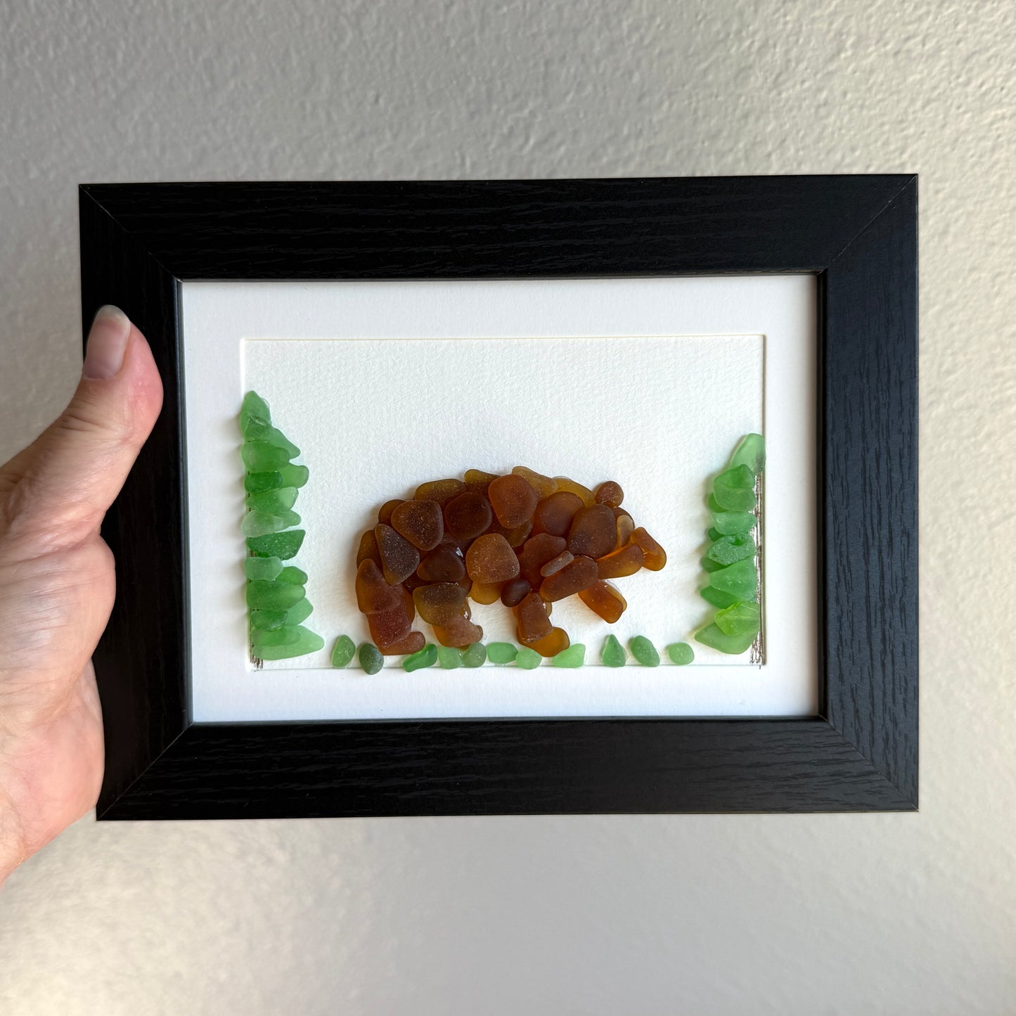 Framed artwork of a bear and trees made from natural materials on a plain background