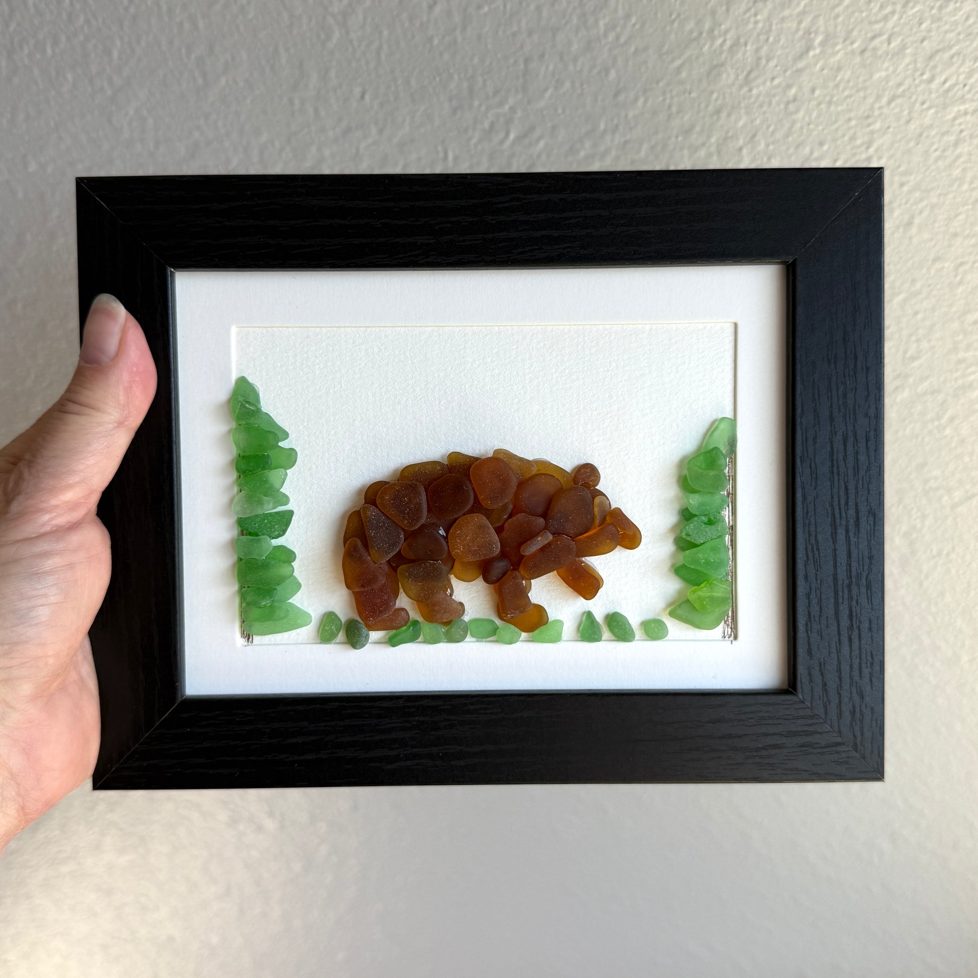 Framed artwork of a bear and trees made from natural materials on a plain background